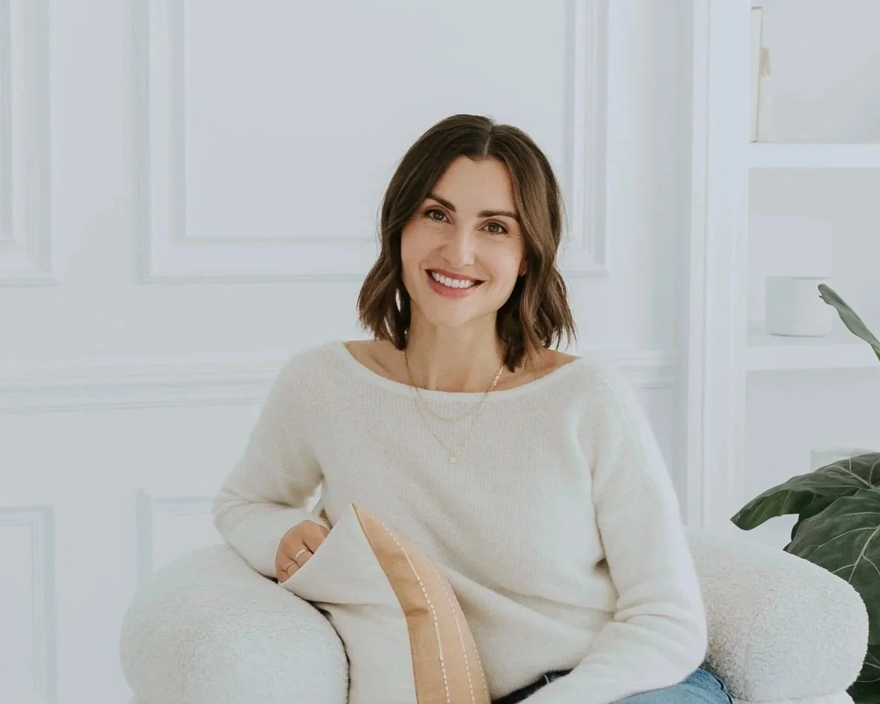 Laura Maksymetz, Registered Psychotherapist, sitting in a chair in a brightly lit therapy office.