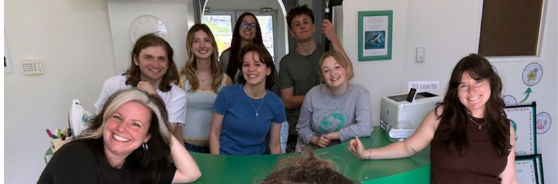 eight staff members smiling at the camera with a faded opacity