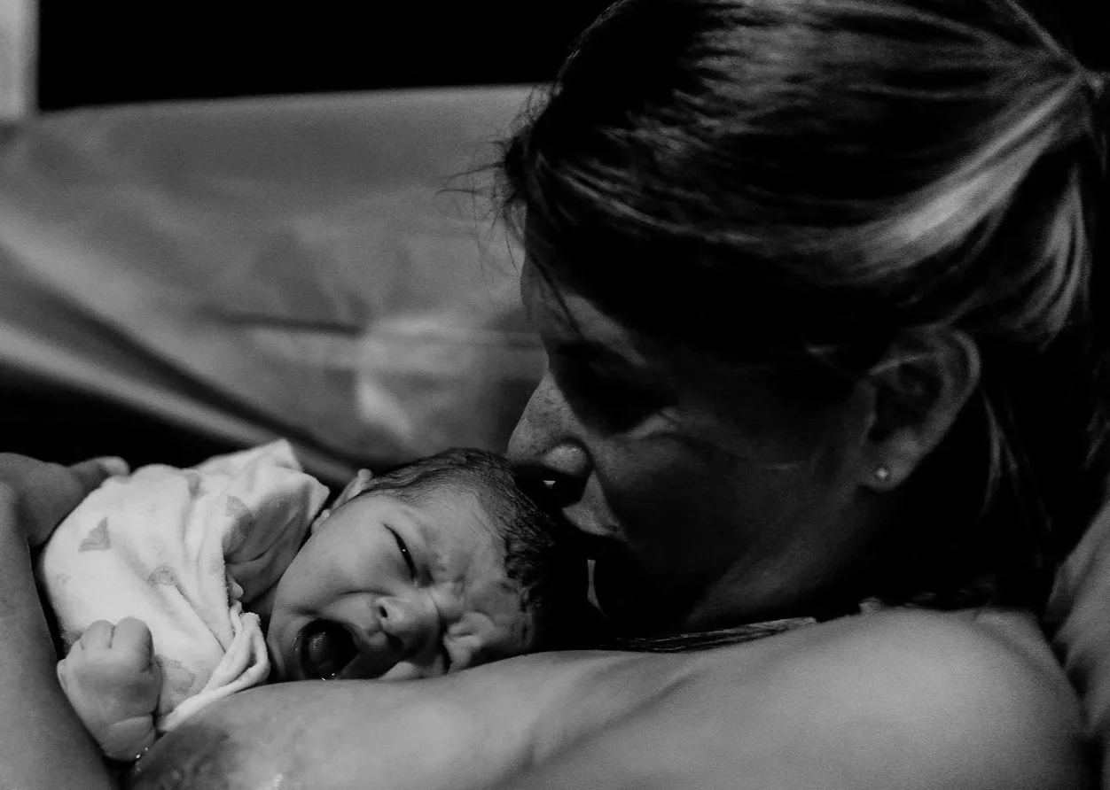 A newborn baby sleeping on a hospital bed covered with a blanket in black and white.