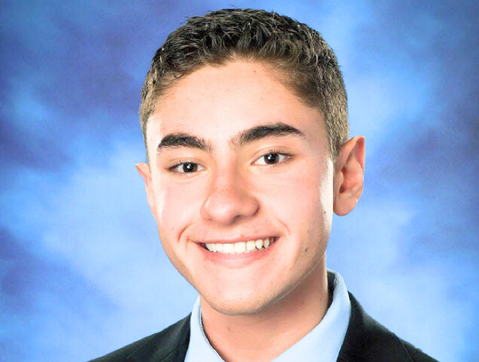 A woman with glasses smiling in front of religious icons.