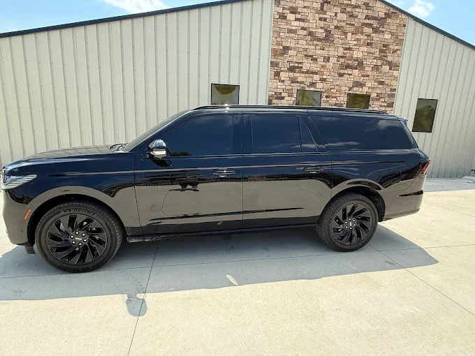 Black SUV parked in front of a beige and brick building on a concrete surface.