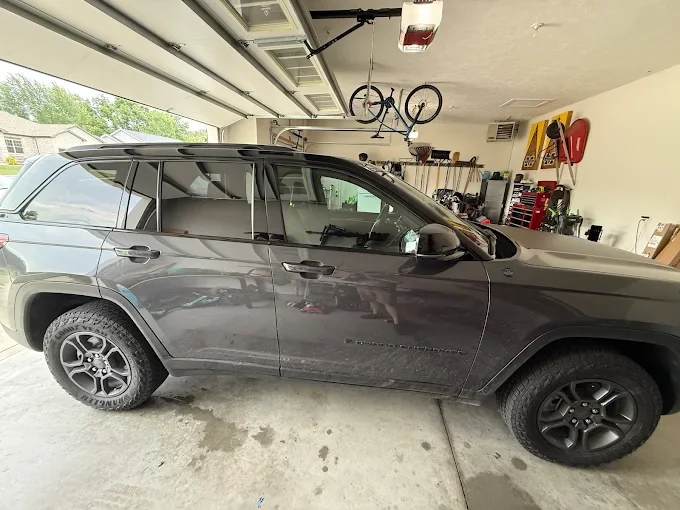 Gray SUV parked inside a garage with tools and a bicycle hanging from the ceiling.