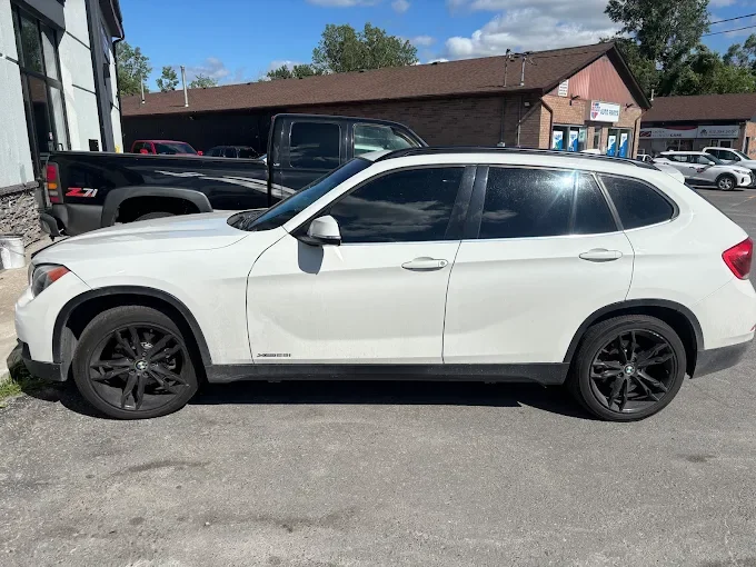 White luxury SUV parked next to a black pickup truck outside a building.