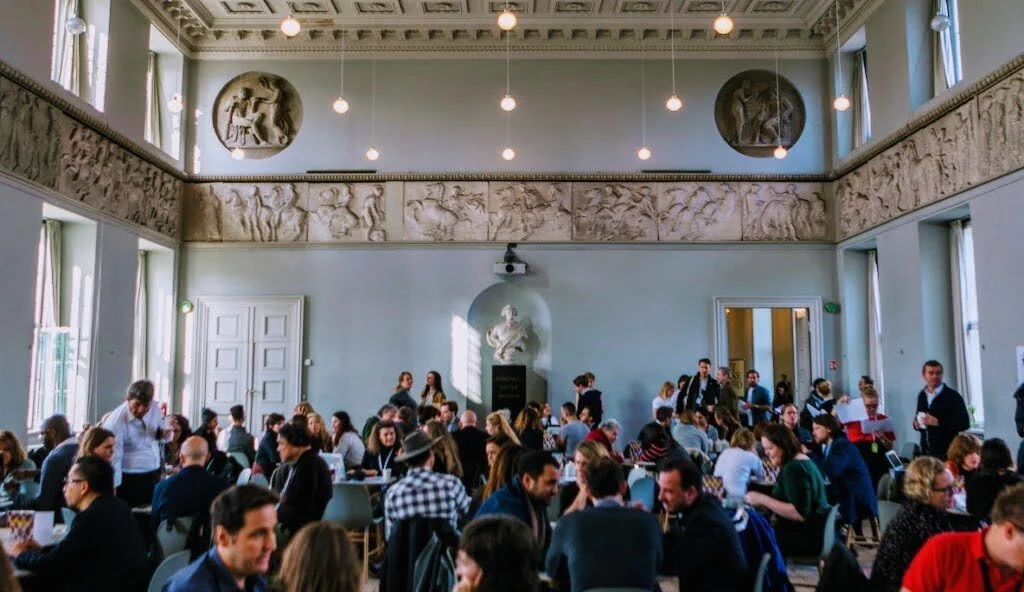 People talking at tables in a classicist room