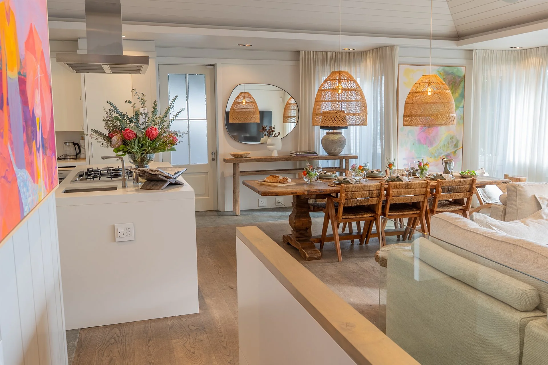 Open-plan living area with access to the beachfront deck through the floor-to-ceiling windows. In the living room and dining area there’s a magnificent artisan wood dining table with space for eight guests. Escape to Cape Town with Simon Escapes. 