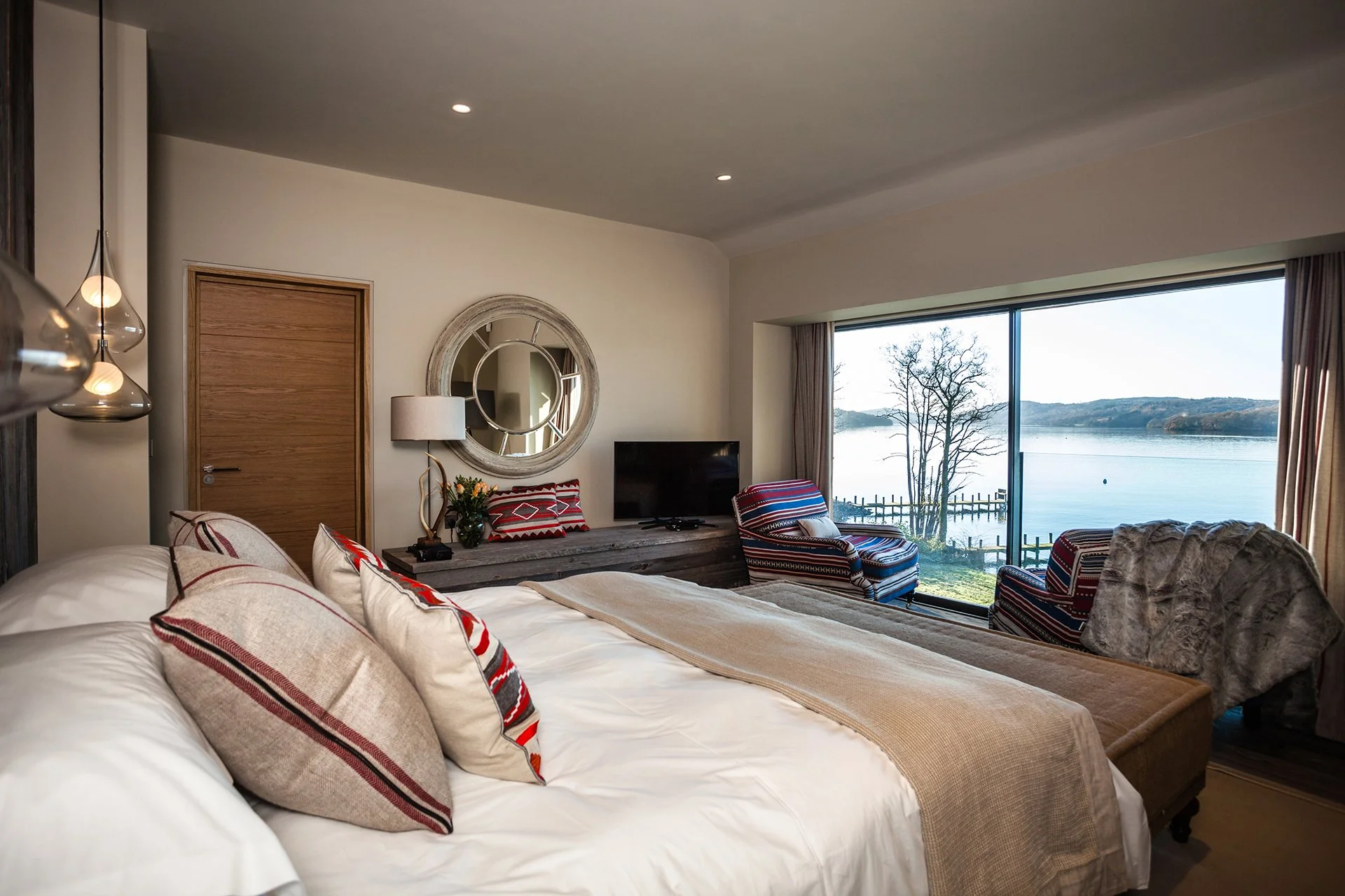 A bespoke glass and stainless steel staircase leads to five en-suite bedrooms with floor-to-ceiling windows, four of which have uninterrupted lake views. Three have balconies. Each has a ViSpring bed, two of which can be made up as twins.