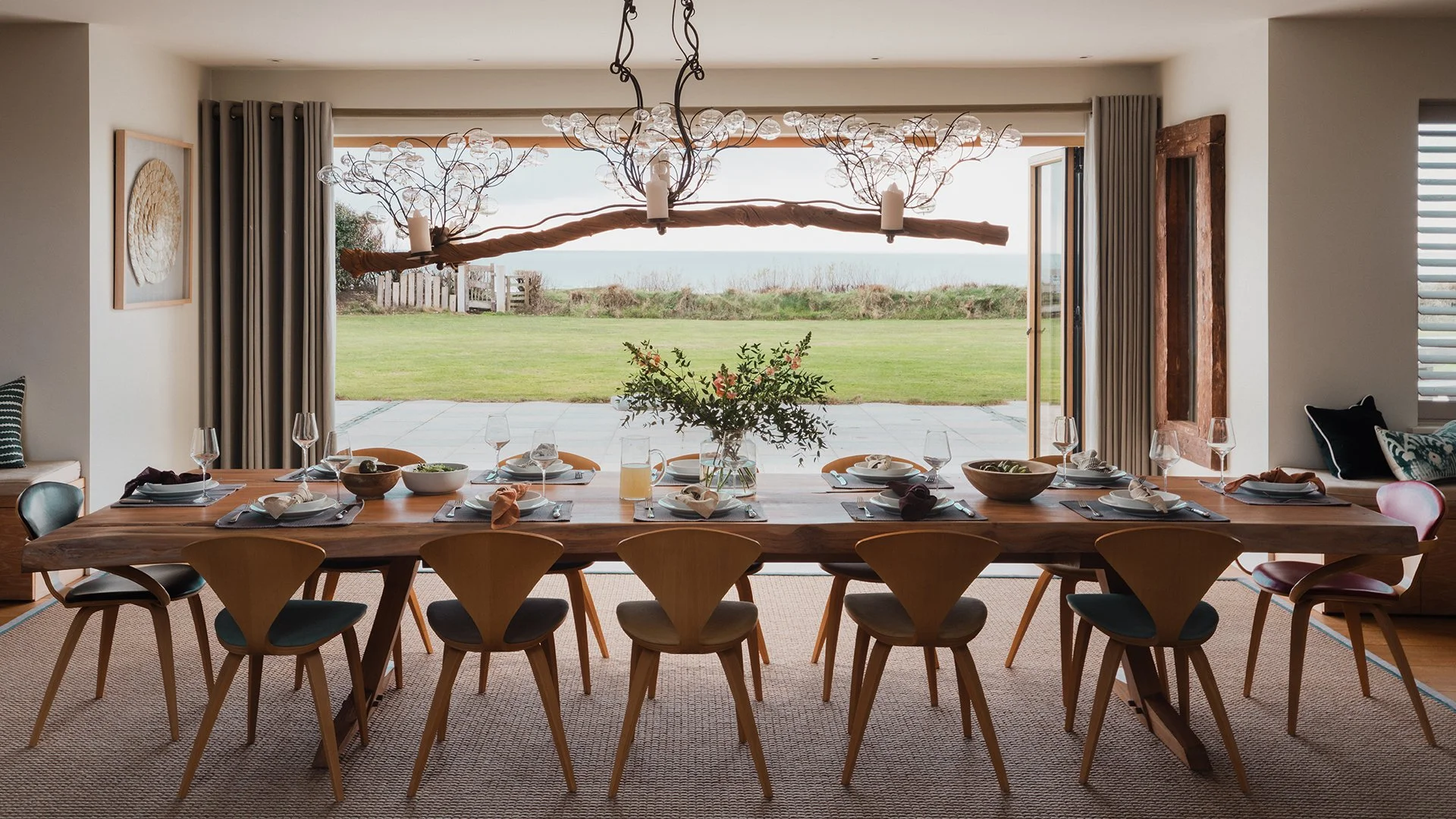 The dining room features a bespoke dining table from New York with Cherner. Doors lead out to the garden terrace and garden - perfect for an evening BBQ. Enquire now for a luxury stay at Little Polgarron, Cornwall.