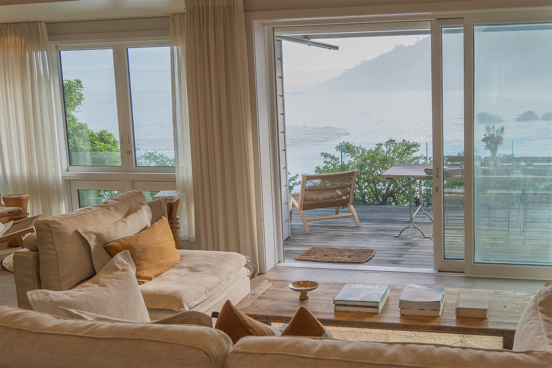 Open-plan space fusing kitchen, dining and living areas with dreamy views and access to beachfront deck through floor-to-ceiling windows. In the living room and dining area there’s a magnificent artisan wood dining table with space for eight guests, 