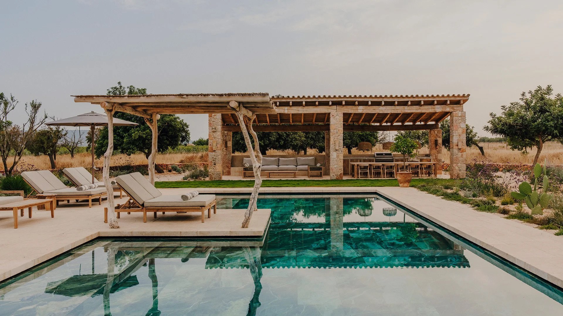 Outside, an expansive terrace frames the inviting swimming pool, while the outdoor kitchen and shaded lounge create an idyllic setting for long, leisurely lunches and relaxed evenings beneath the Mallorcan sky.