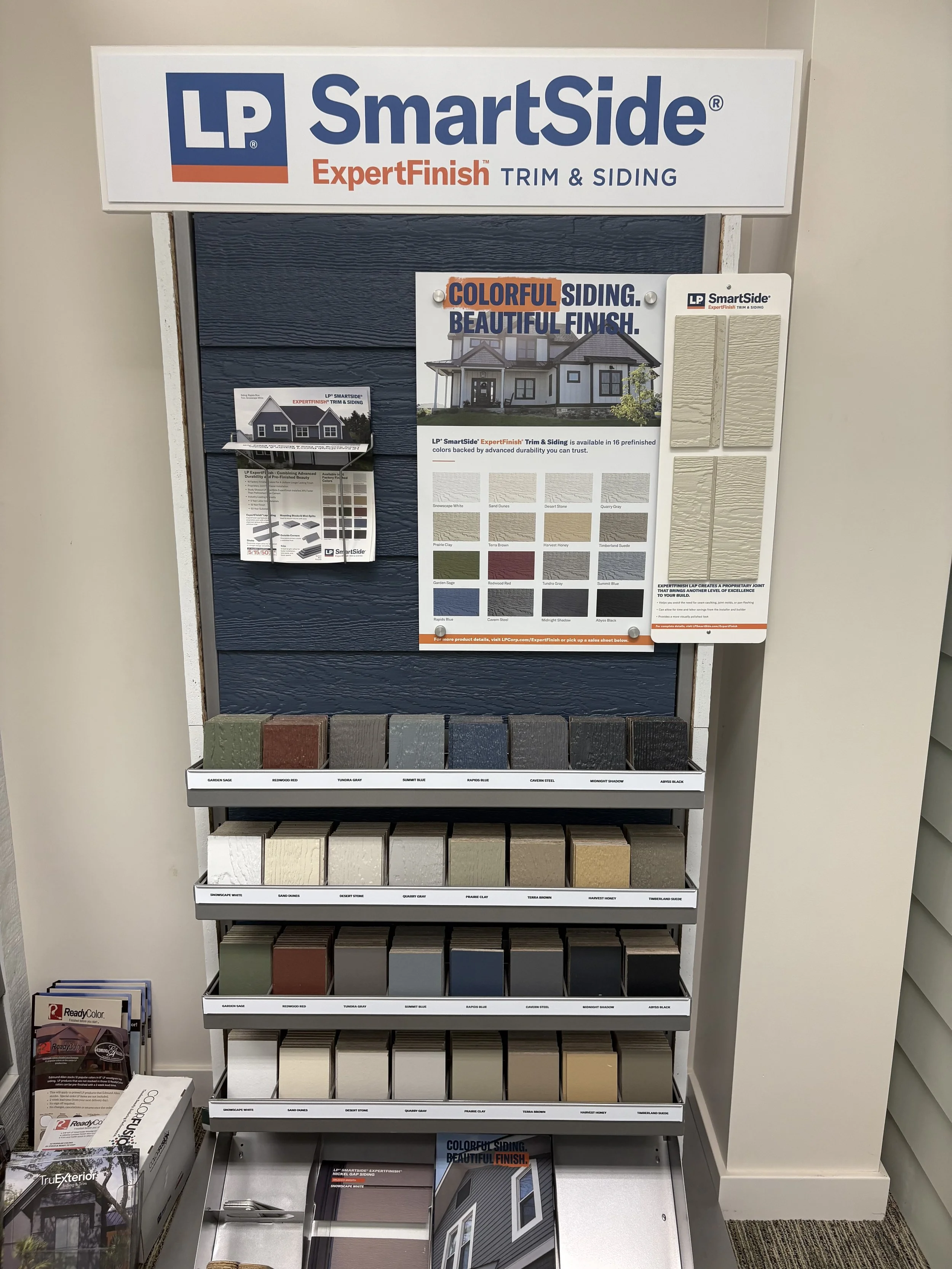 Display of various siding color samples and informational brochures at a home improvement store, with the LP SmartSide brand logo above.