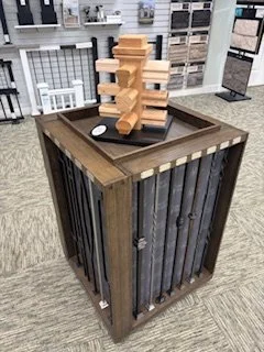 A wooden display table in a showroom, with multiple wooden handrail options stacked in a tower and railing spindle options on display around the spinning table.