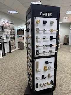 Display stand with various door hardware and locks, labeled 'EMTEK', in a retail store setting.