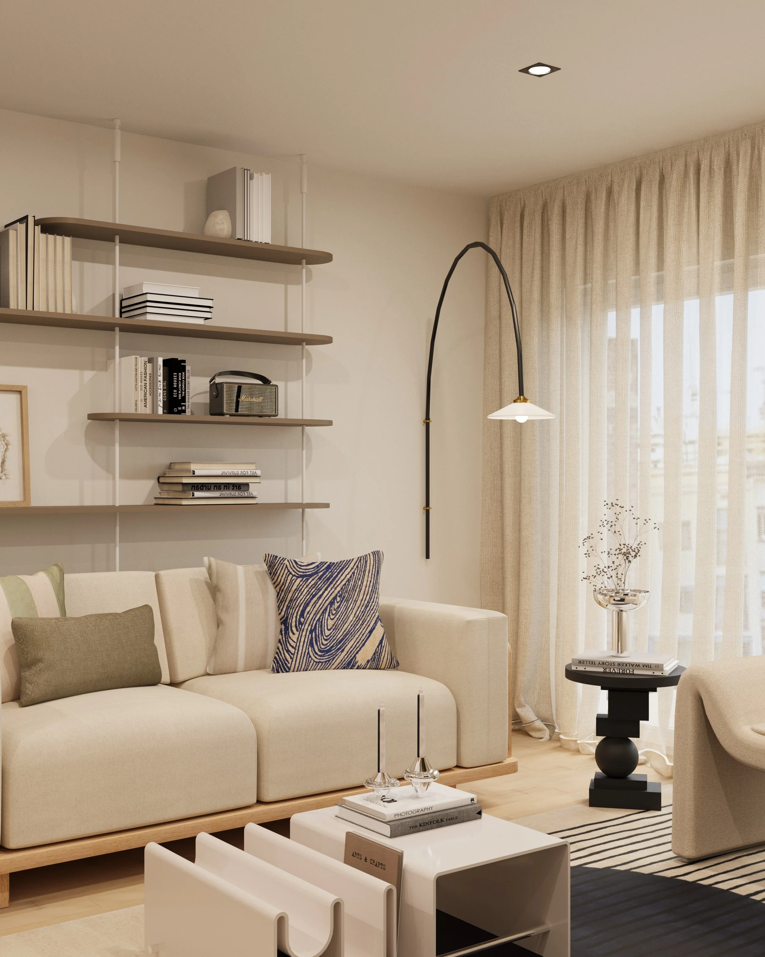 A cozy living room with beige curtains covering large windows, a cream armchair, black and white striped rug, white side table with art books and a decorative plant, and a white TV console with a framed abstract art piece and decorative vase.
