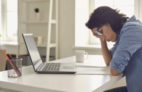 Graduate frustrated at laptop while applying for jobs.