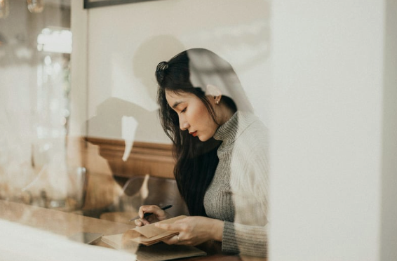 Woman in cafe with notepad contemplating