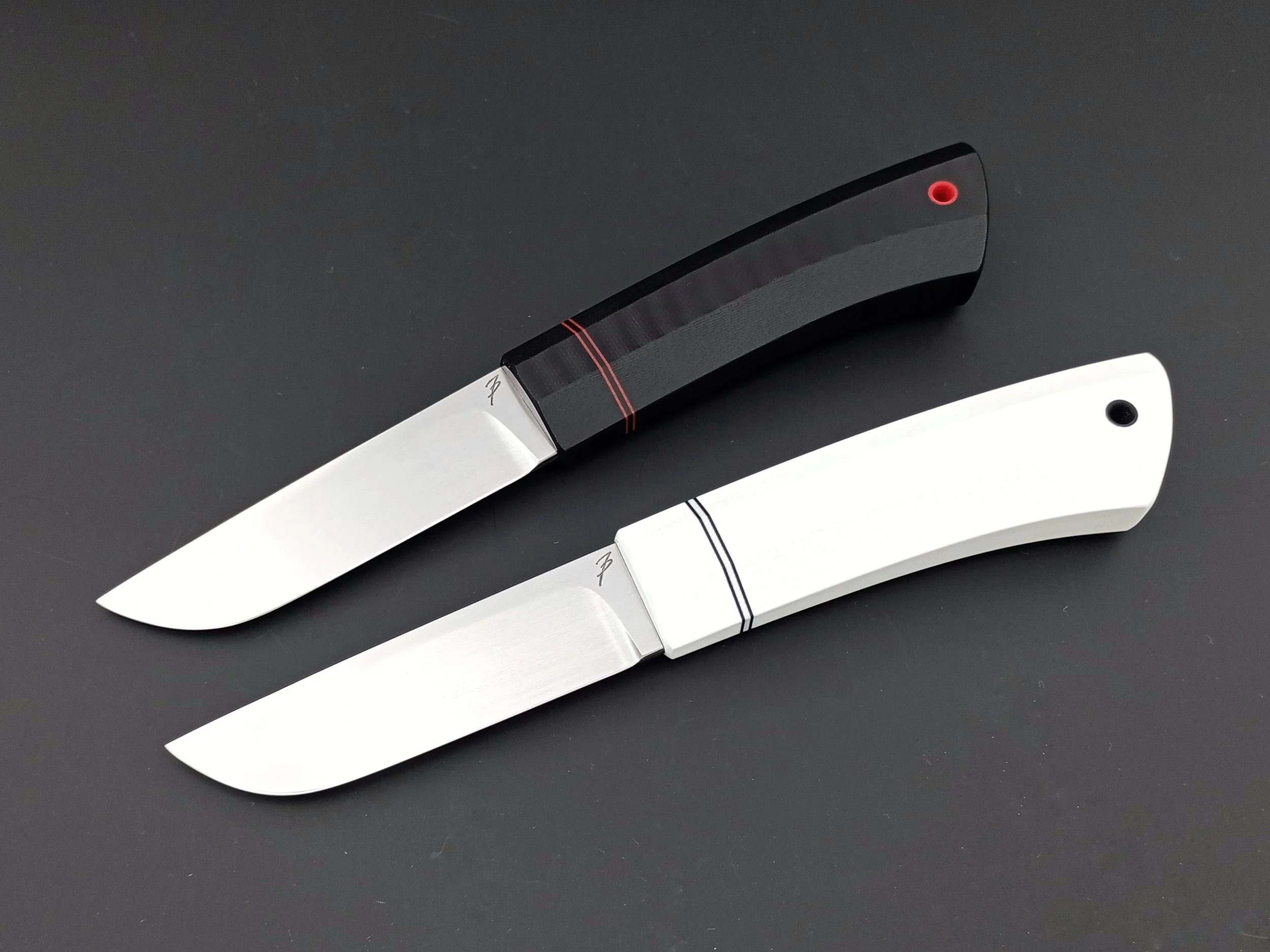 Two outdoor knives with black and white handles.