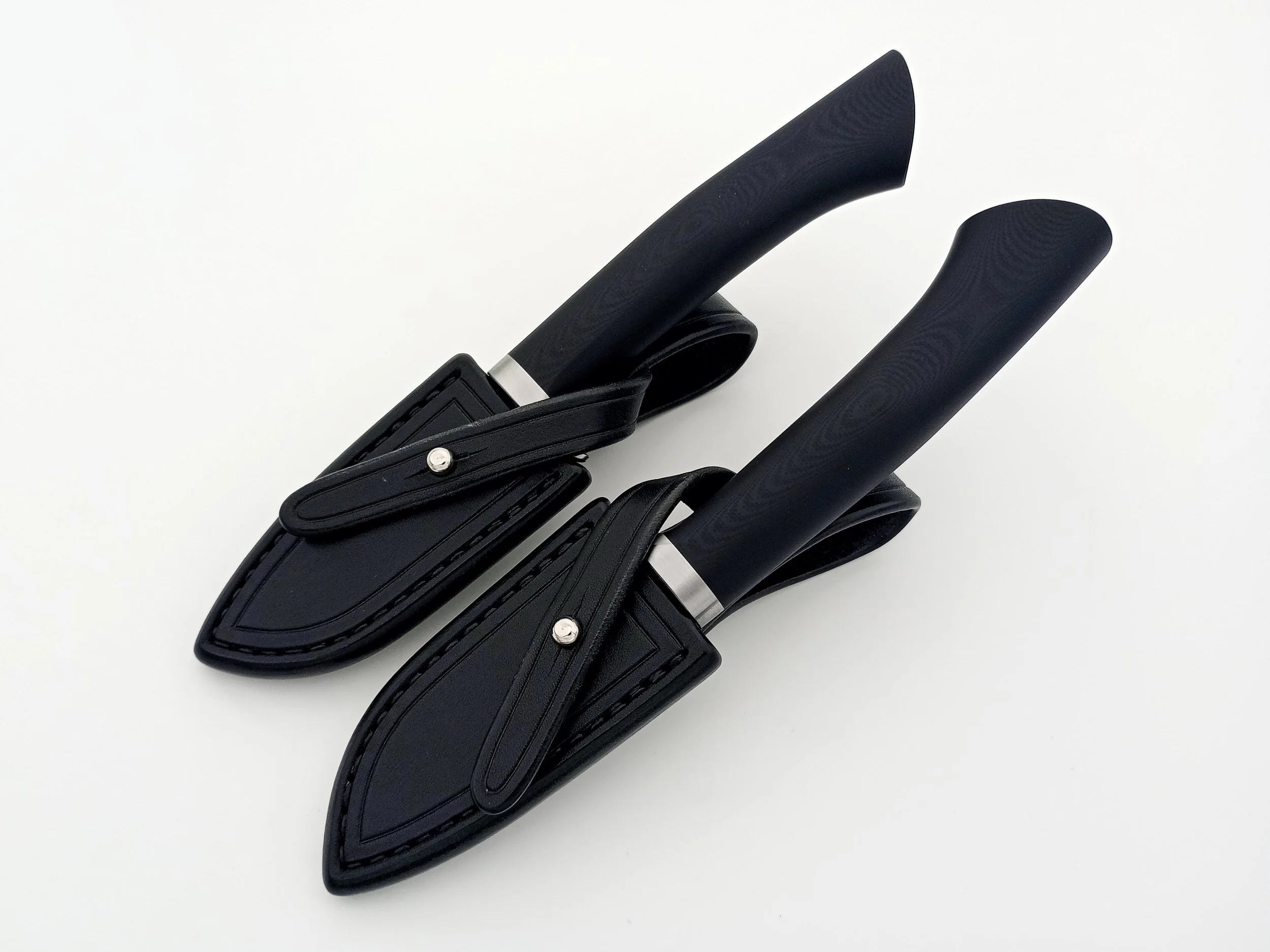 Two hunting knives in their leather sheaths.