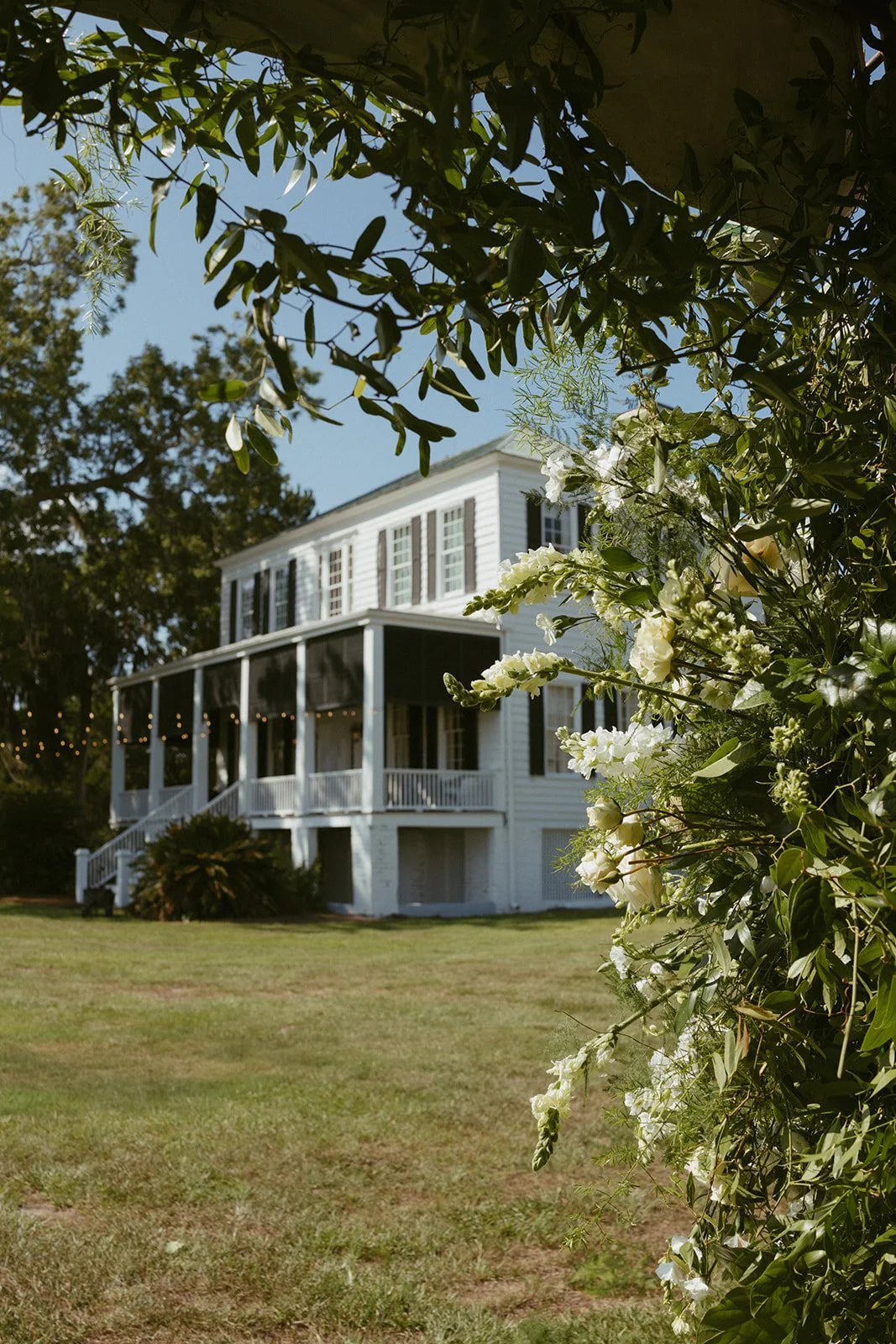 Southern wedding floral installation at Agapae Oaks on St. Helena Island South Carolina featuring lush greenery ceremony florals with historic Lowcountry estate wedding venue in background.
