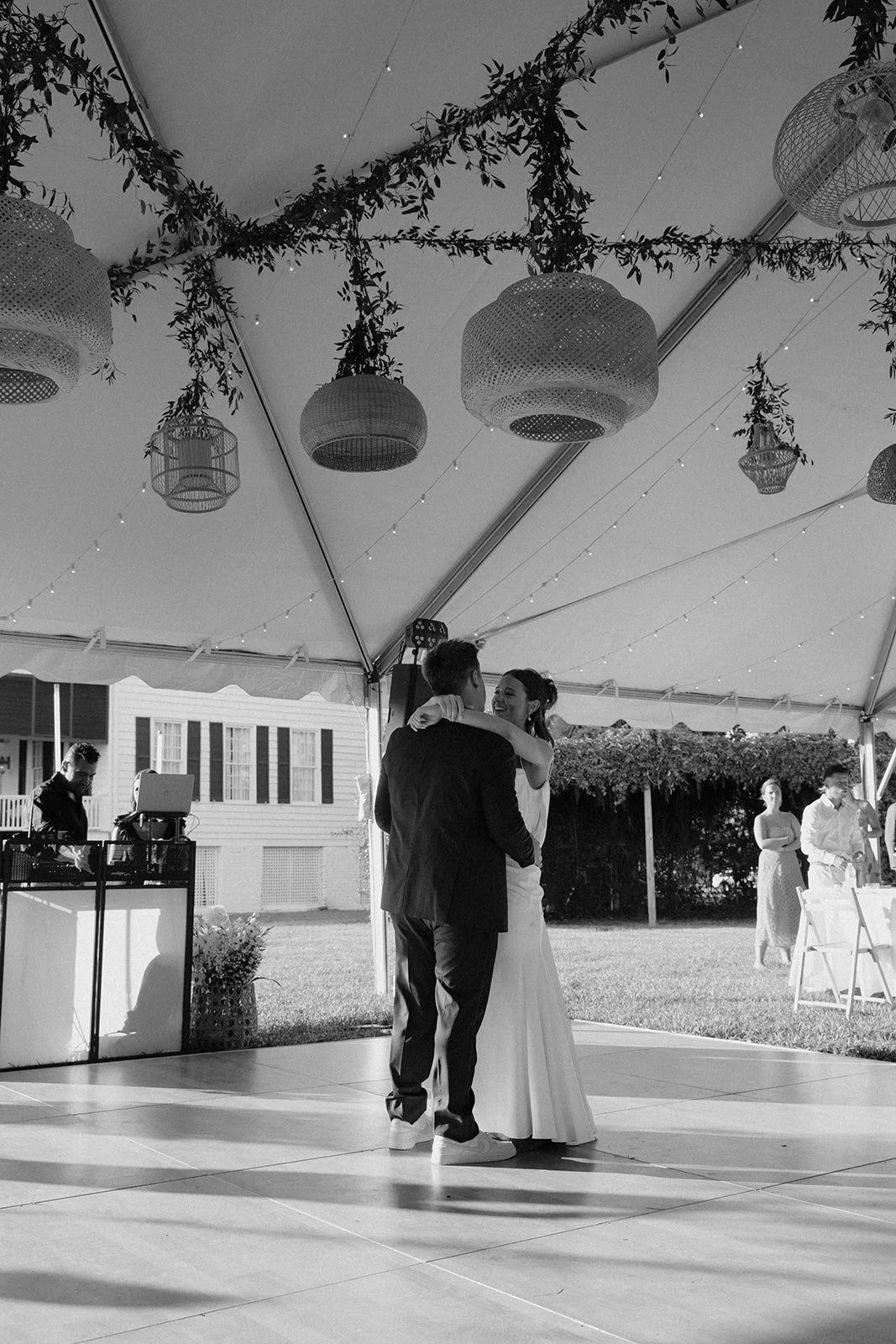 Bride and groom first dance under greenery ceiling installation at tented wedding reception at Agapae Oaks on St. Helena Island South Carolina Southern destination wedding venue.