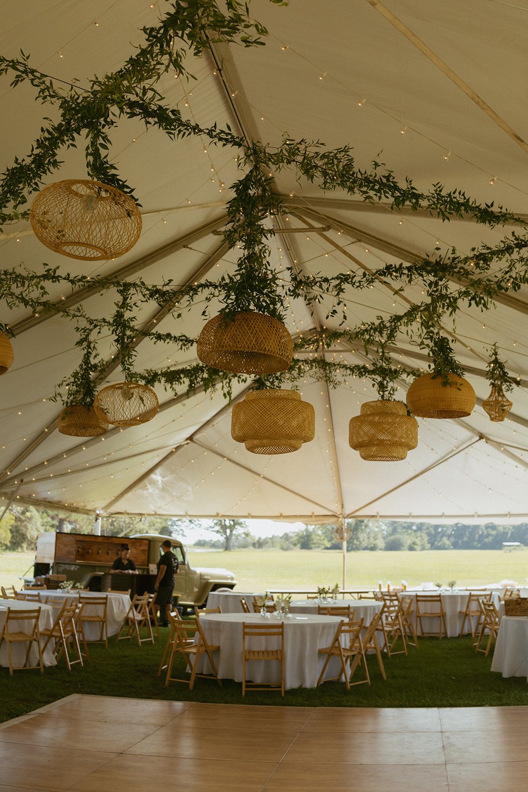 Elegant tented wedding reception at Agapae Oaks on St. Helena Island South Carolina featuring hanging greenery installation, woven rattan pendant lighting and romantic outdoor Southern destination wedding design.