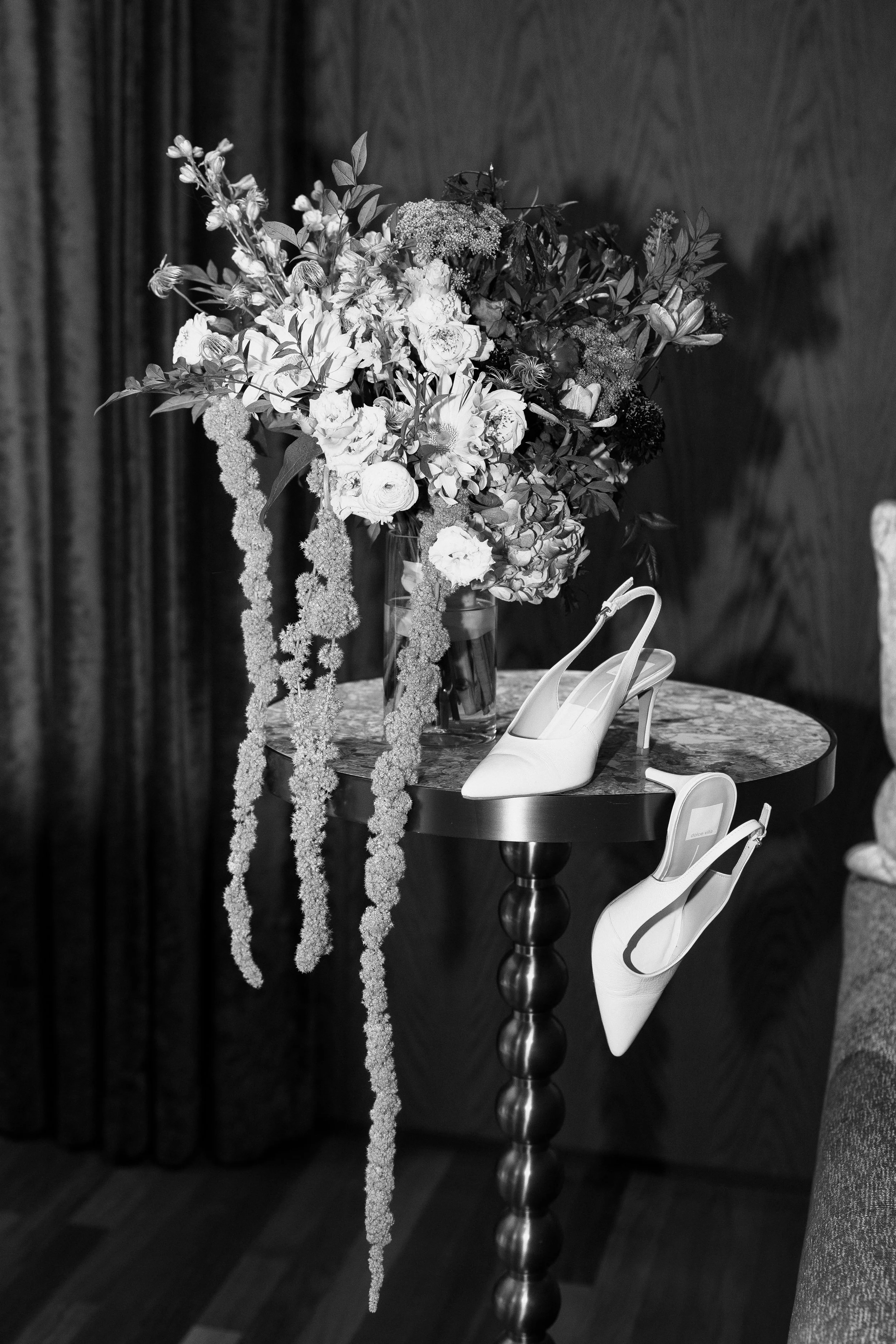 Black and white editorial wedding still life featuring a lush floral arrangement and modern bridal heels styled for a Savannah, Georgia wedding by Ivory & Beau.
