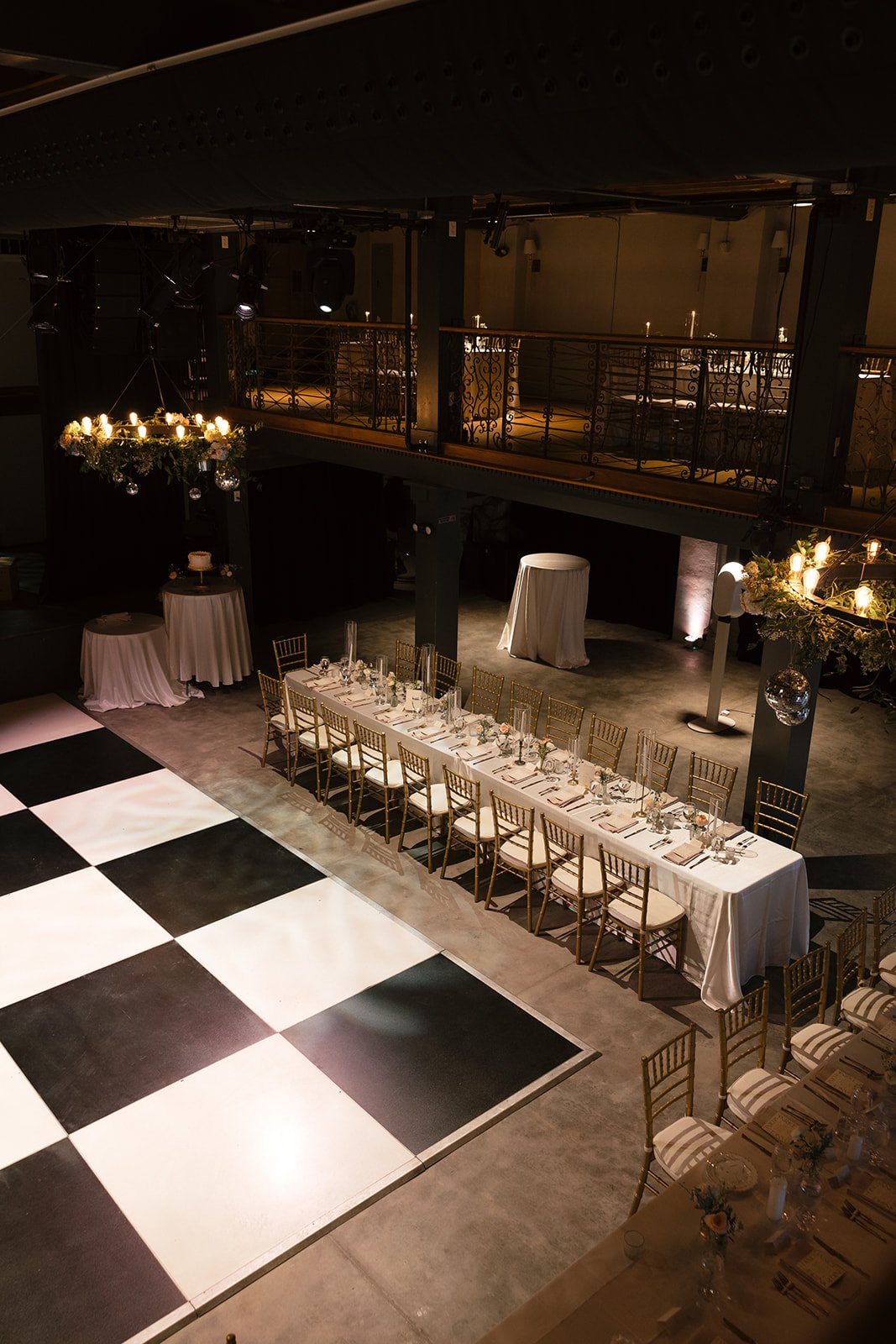 Wedding reception setup at Victory North in Savannah, Georgia featuring black and white dance floor, elegant reception tables, candlelight, and floral installations by Savannah wedding florist for modern industrial venue celebration.