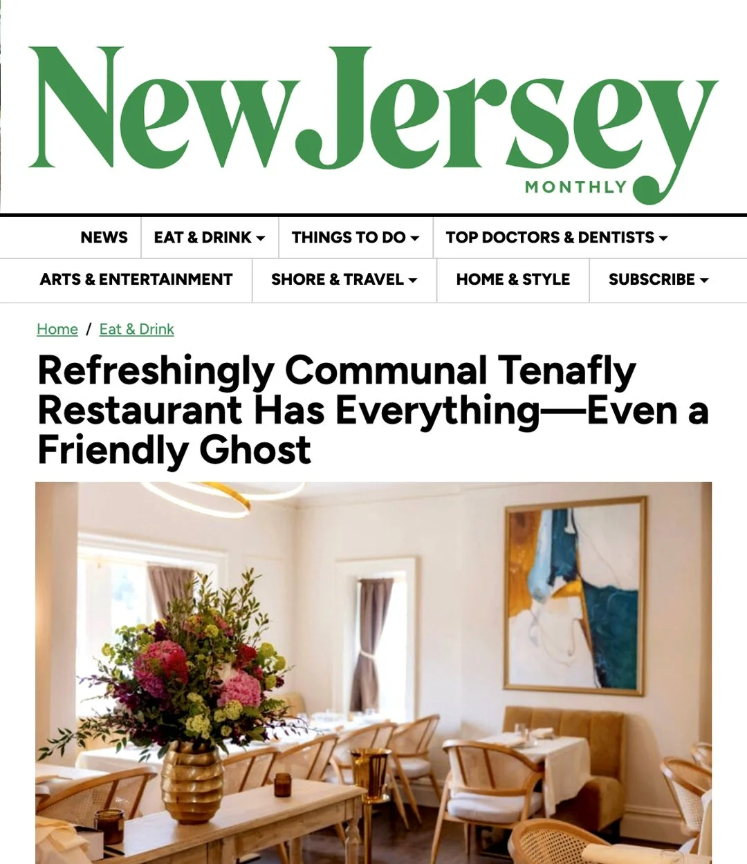 Interior of a bright dining room with a large floral centerpiece, framed artwork, and dining tables with chairs.