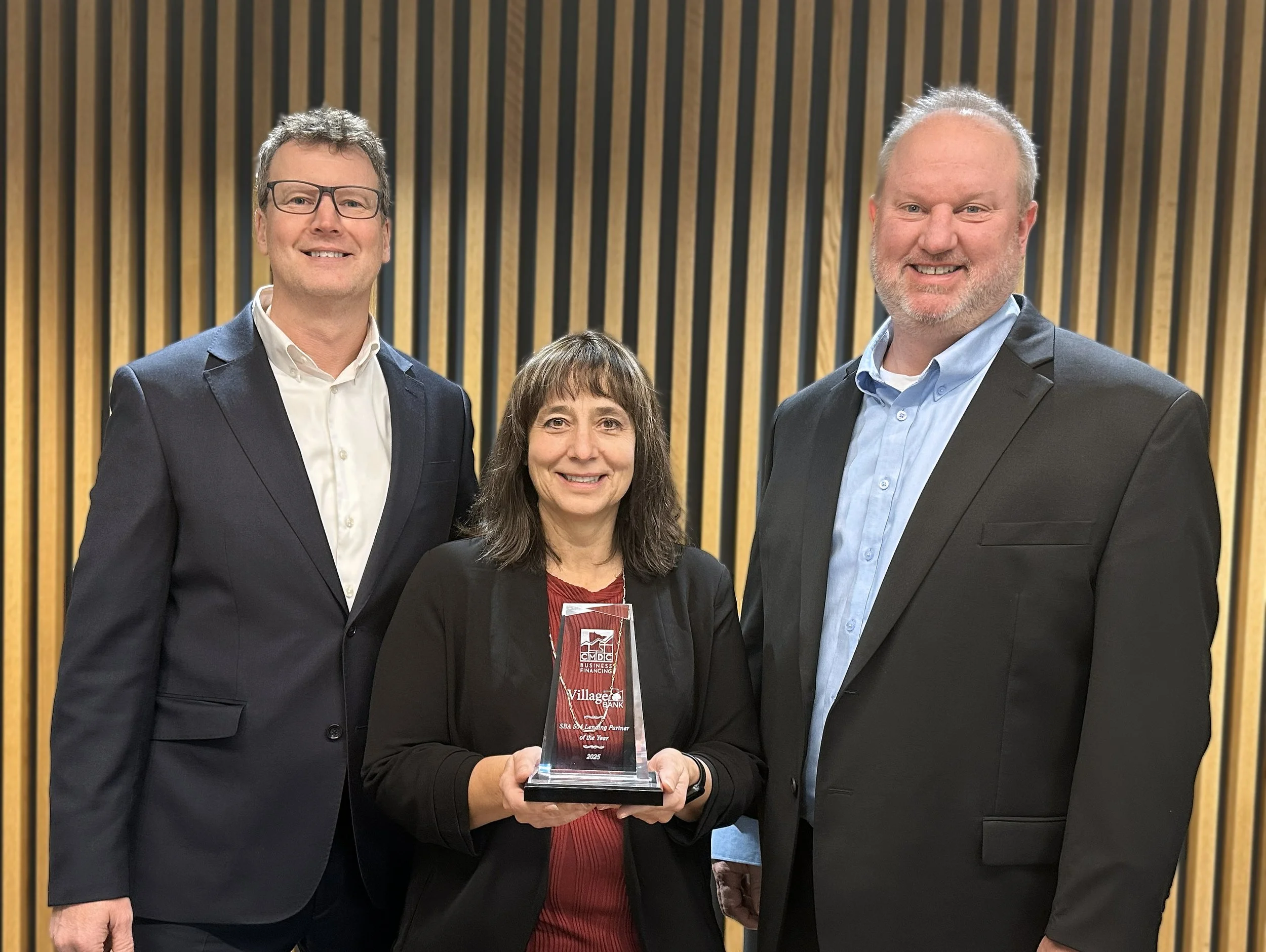 Photo of Village Bank President, Kraig Kliber, Chief Credit Officer, Michelle Anderson holding the 2025 CMDC trophy, and EVP Commercial Sales Leader Kyle Kray