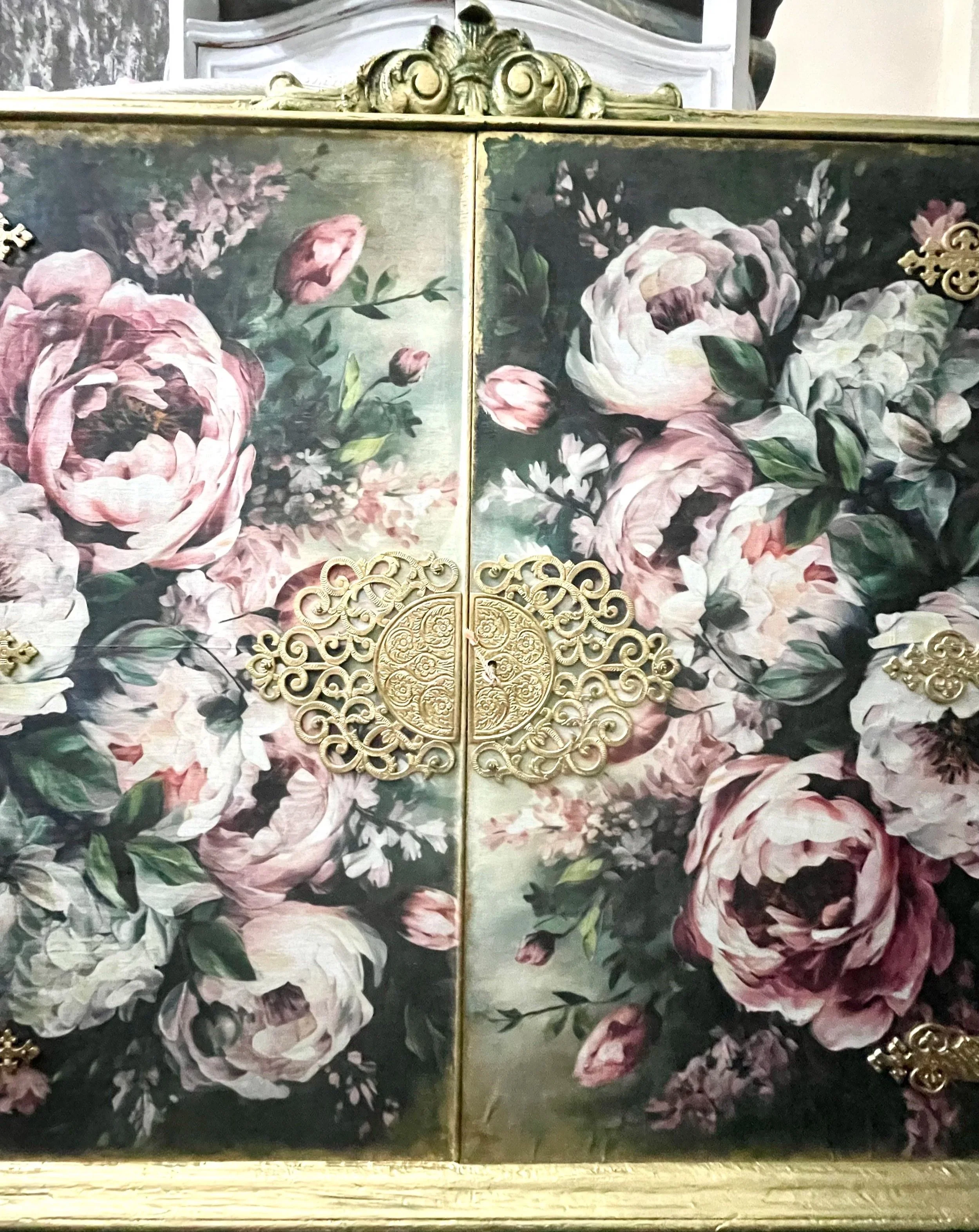 Close up of the top doors of a Queen Anne double wine cabinet hand painted in green and gold showing an ornate gilded vintage style gold filigree lock plate
