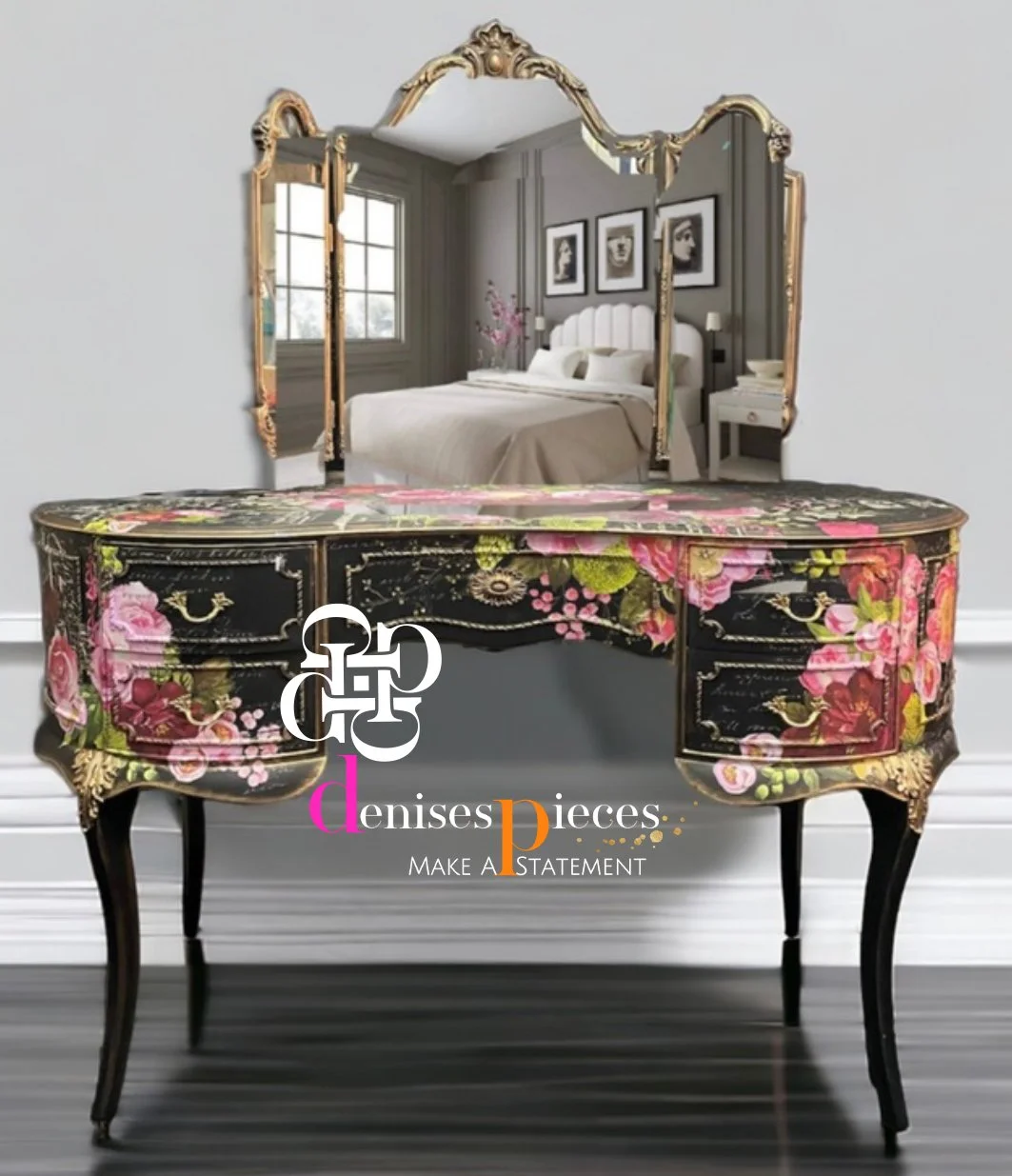 A decorative table with floral patterns and a logo in front of a large ornate mirror reflecting a bedroom with a bed, framed photos on the wall, a nightstand, and a window.