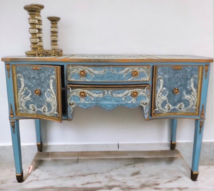 Vintage blue and gold ornate sideboard with two cabinet doors and three drawers, topped with a decorative candle holder on a marble floor.