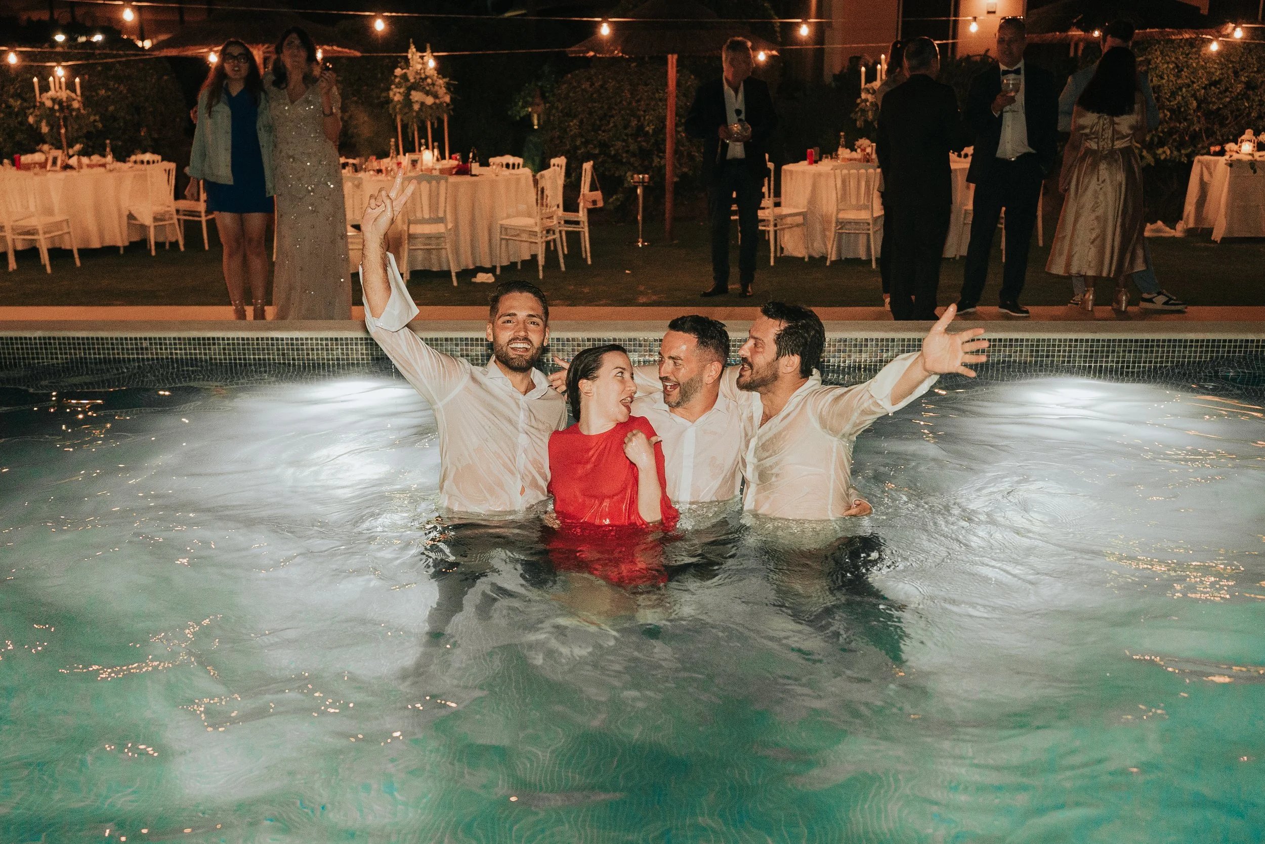 Bride and groom jumping into the pool at the end of the wedding party