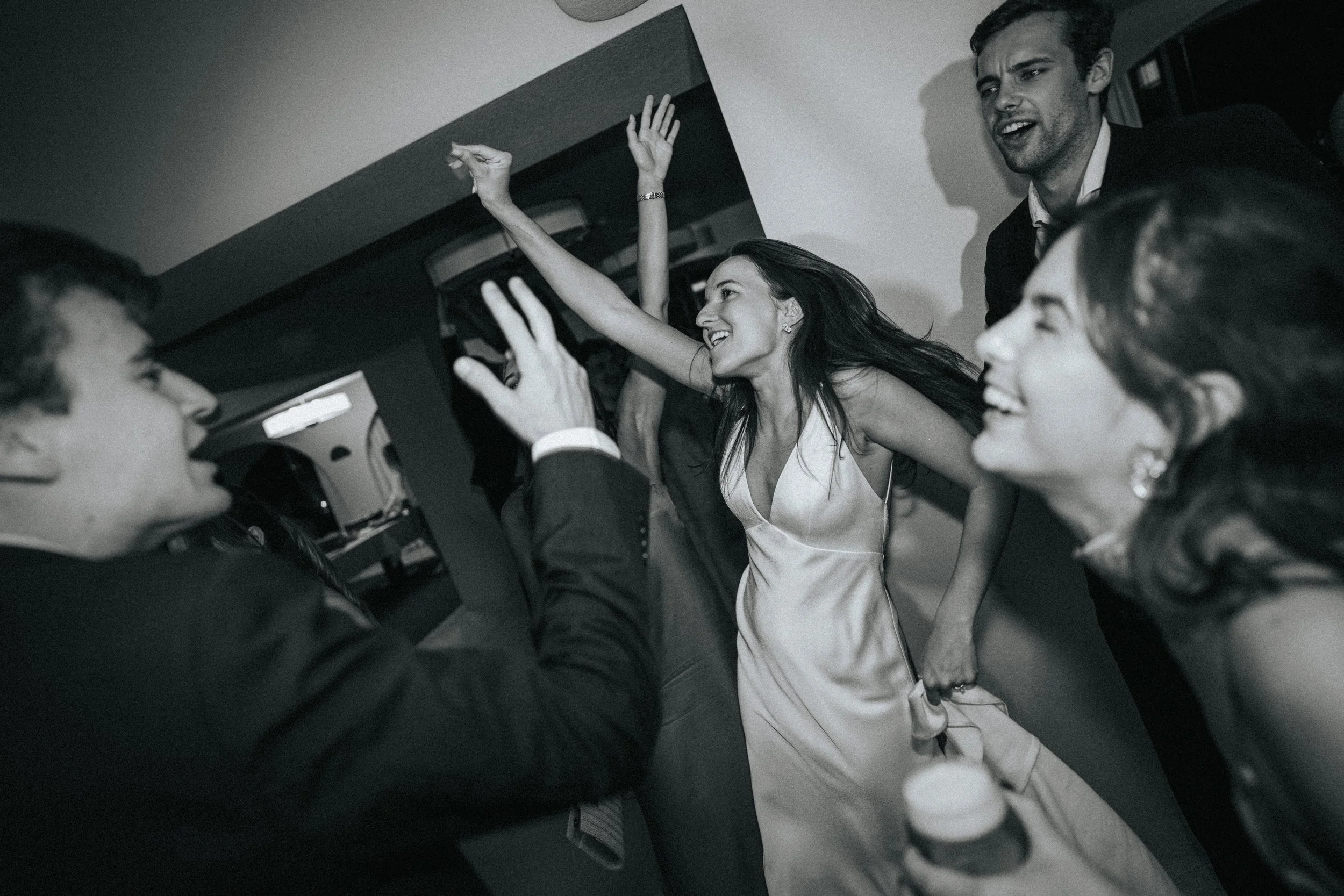 Group of friends celebrating and having fun, smiling, laughing, and dancing at a party or social gathering.