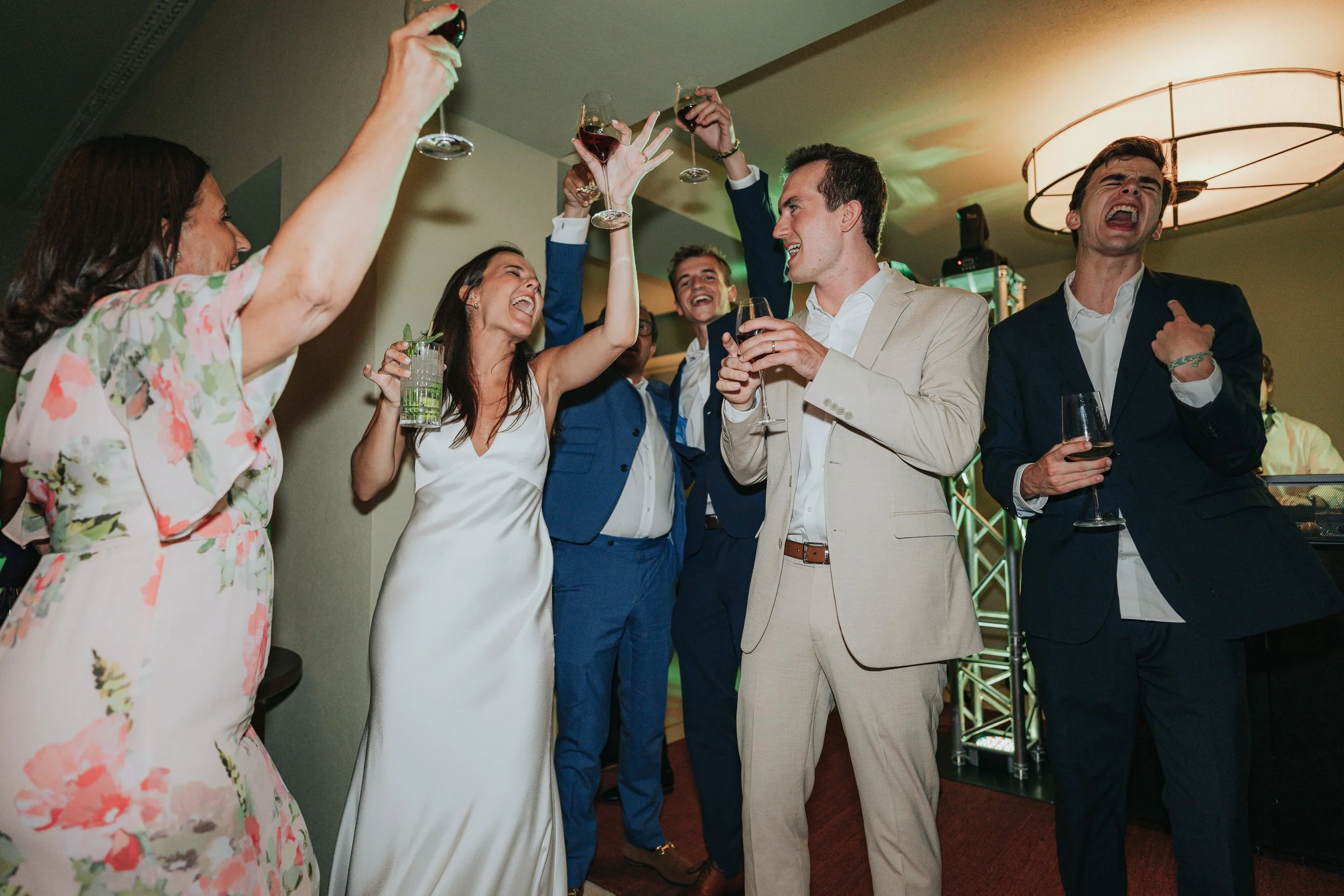 Group of people at a celebration raising glasses of wine and smiling