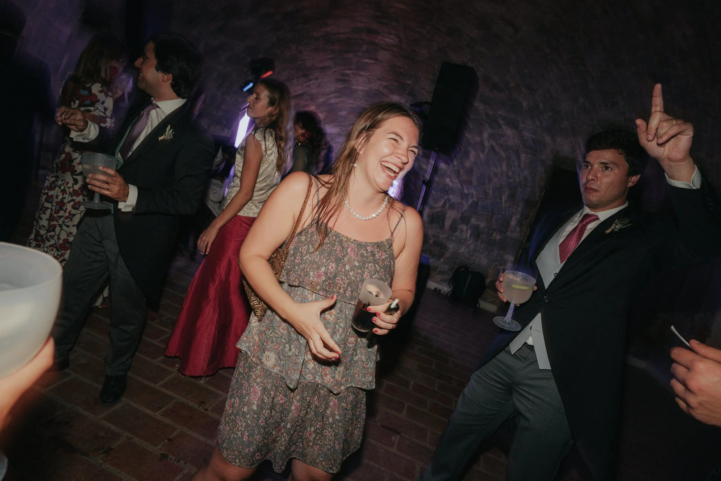 People dancing and socializing in a dimly lit, brick-walled venue.