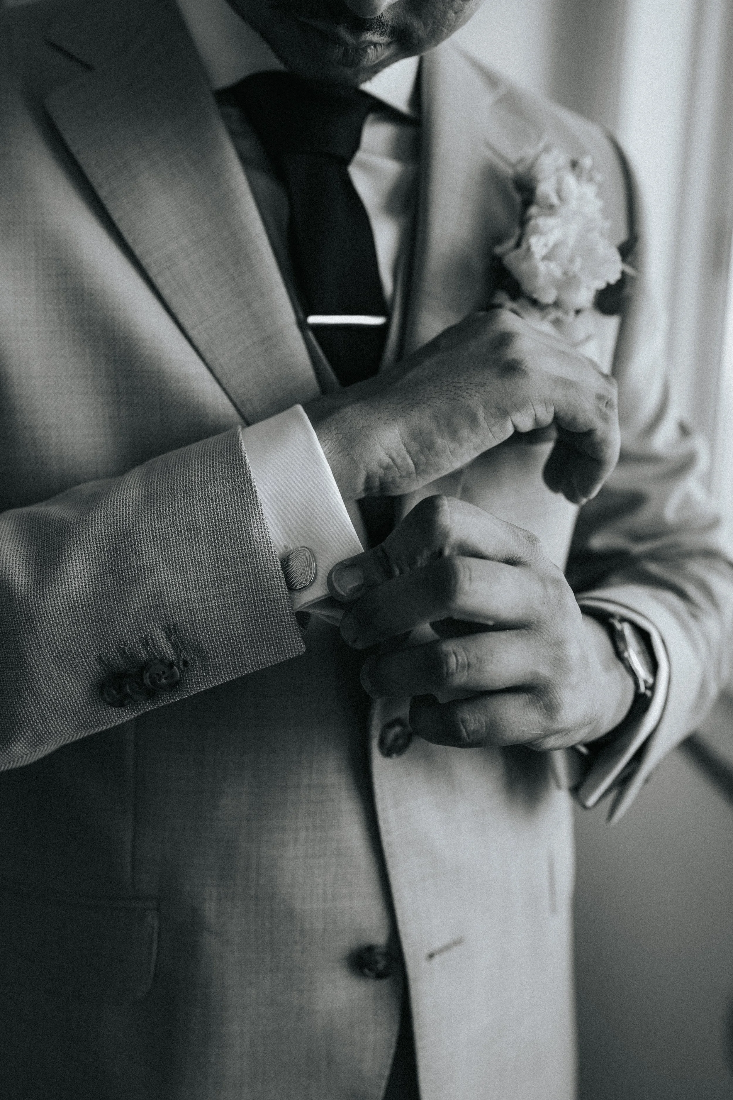 Close-up of a man in a suit adjusting his cufflink.