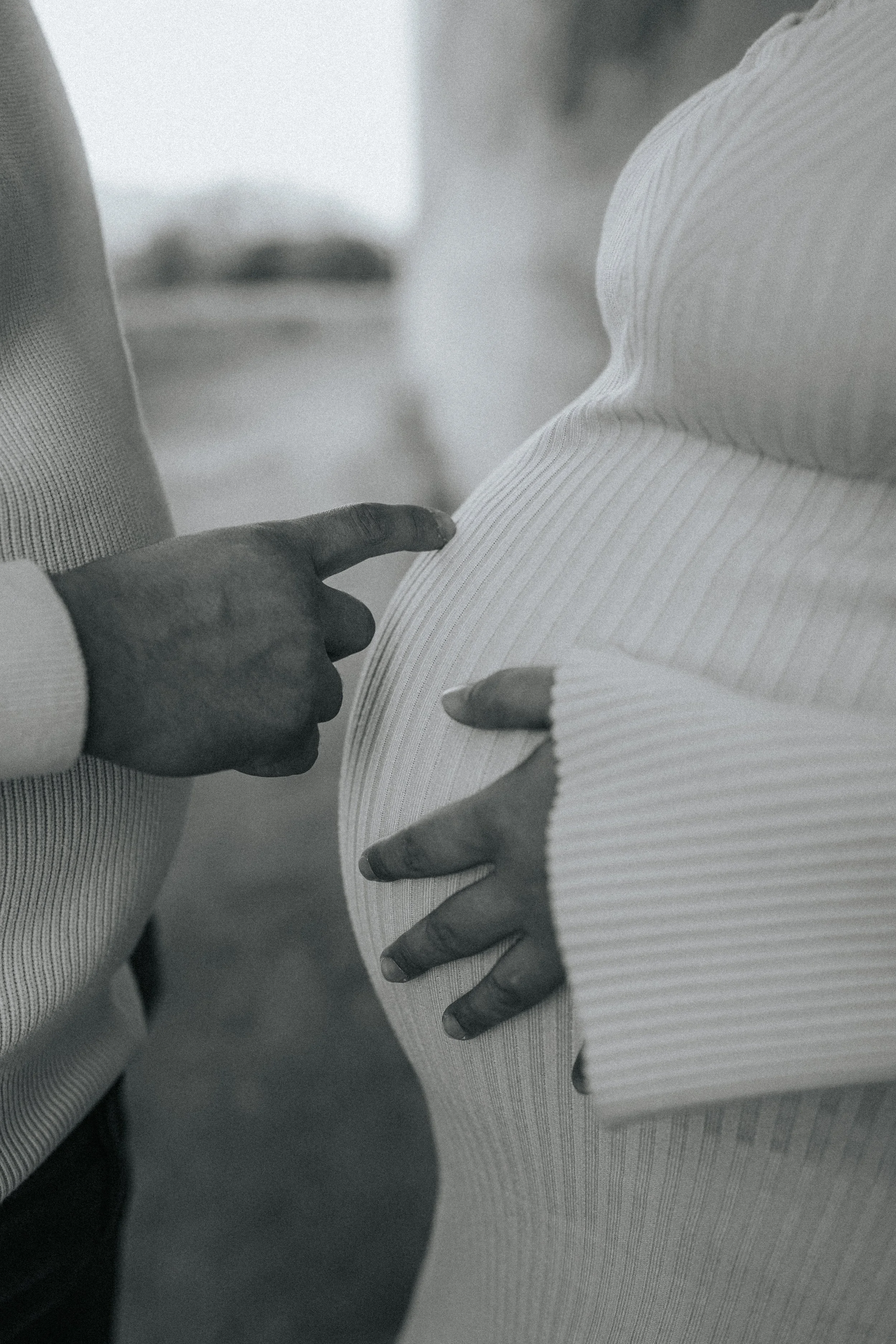 Close-up of two hands touching a person's upper arm and shoulder, with the focus on the hands and arm.