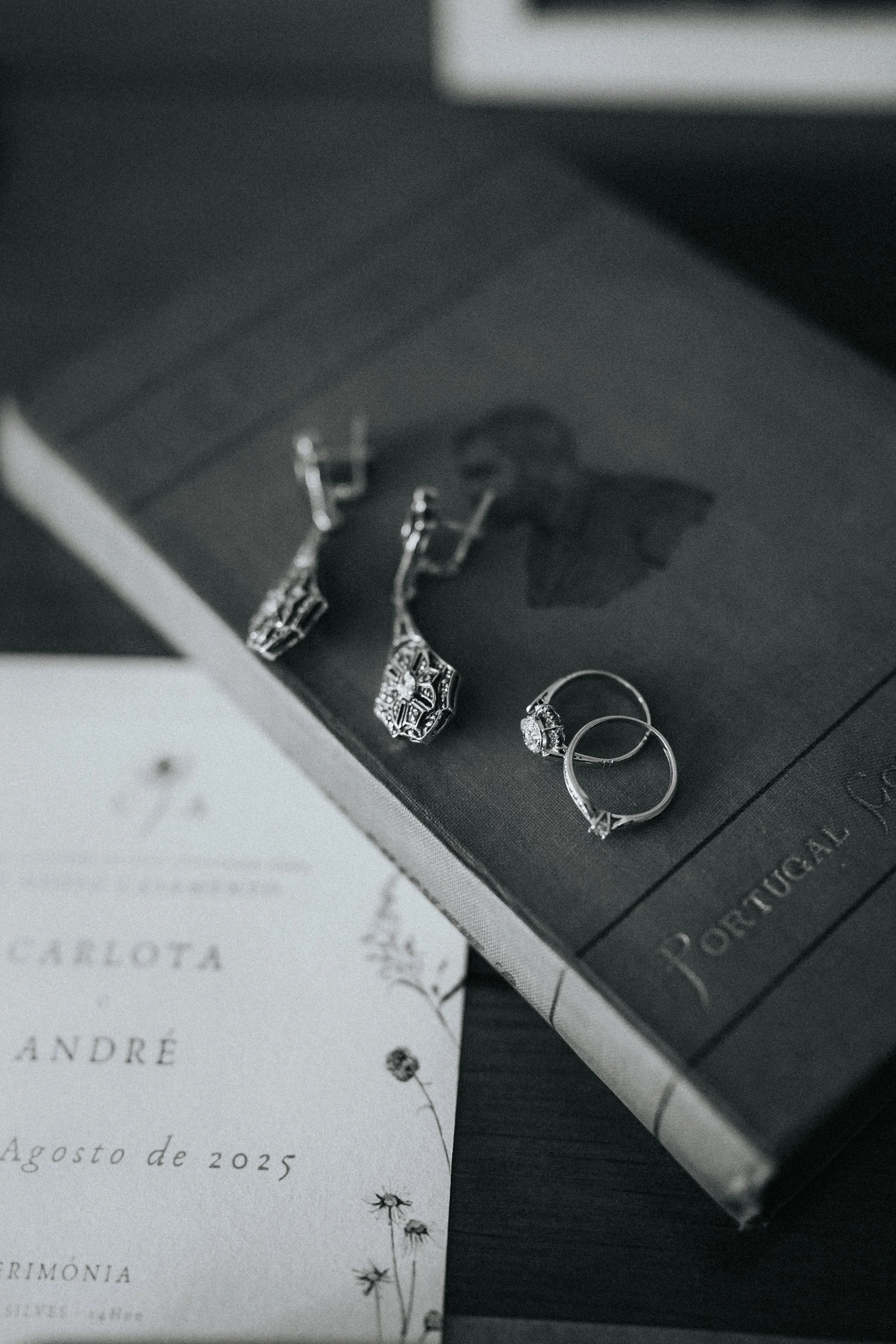 A black box containing jewelry, including earrings, with a book underneath and a handwritten letter with a flower illustration in the background.