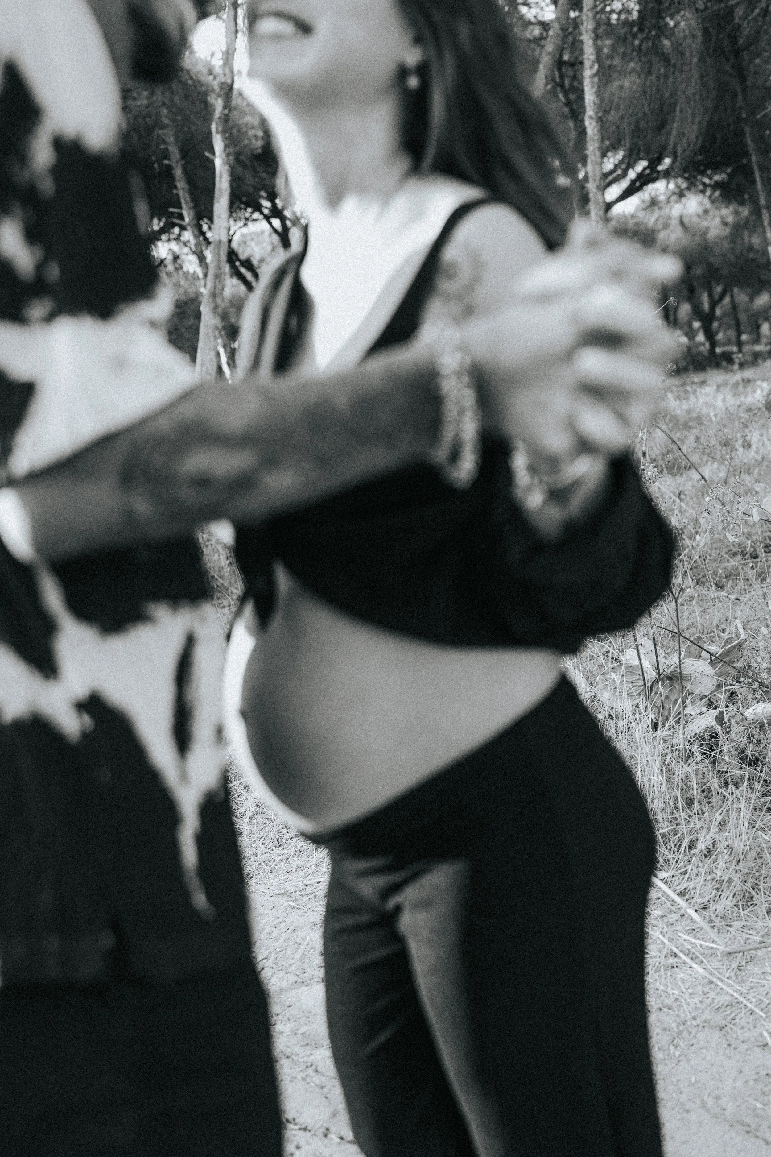 Black and white photo of two women holding hands in a natural outdoor setting with trees and grass in the background