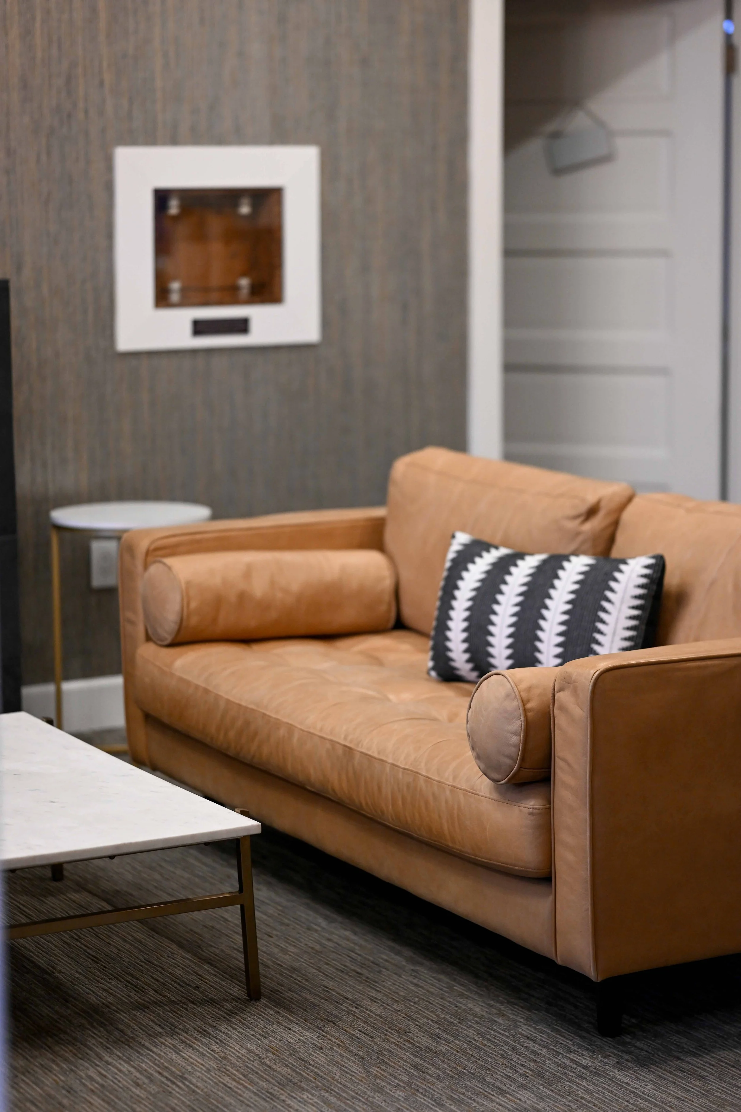 A beige leather sofa with black and white decorative pillow in a modern living room.