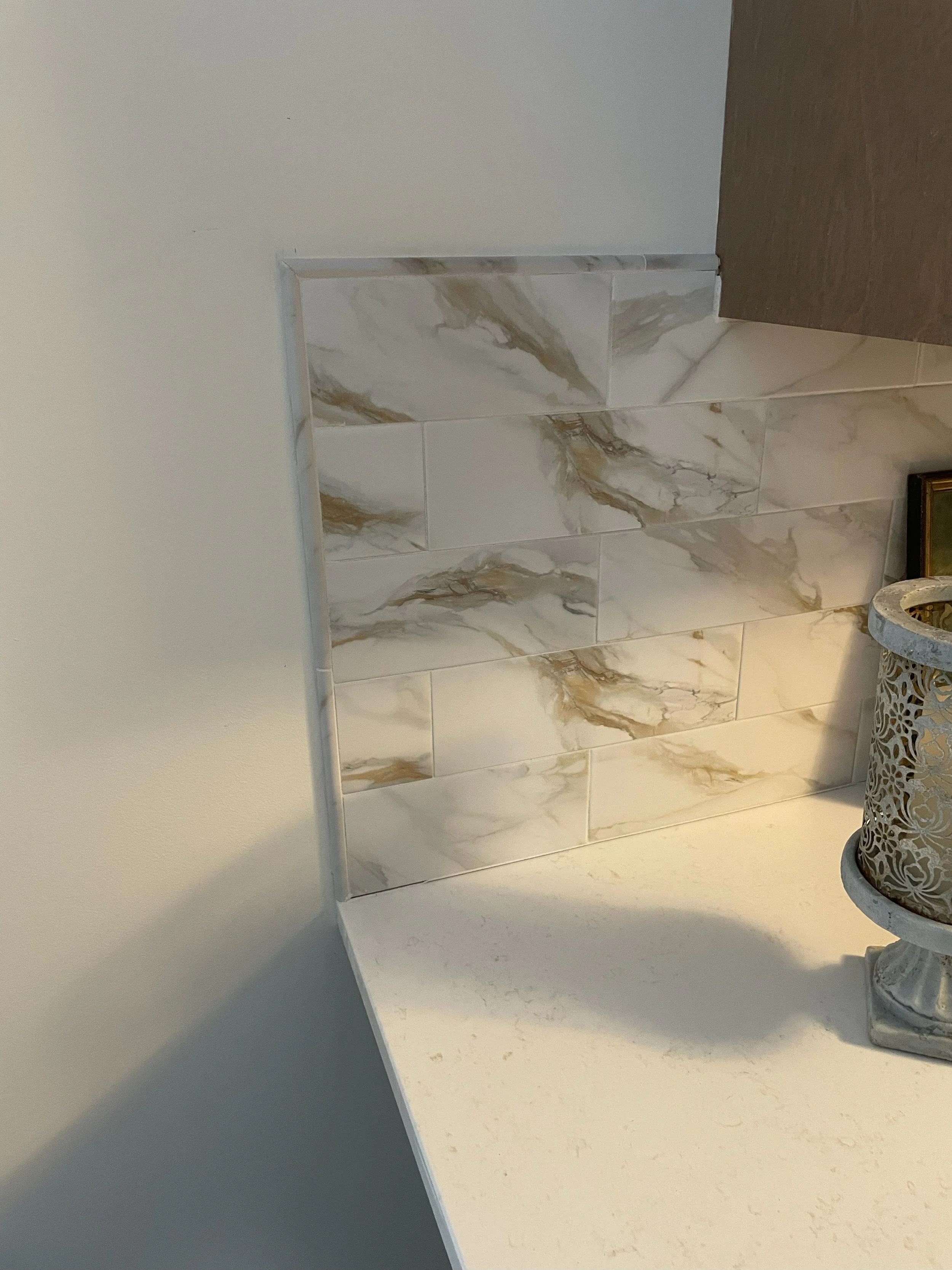 Close-up of a kitchen countertop with a decorative tiled backsplash and a decorative container with an intricate pattern.