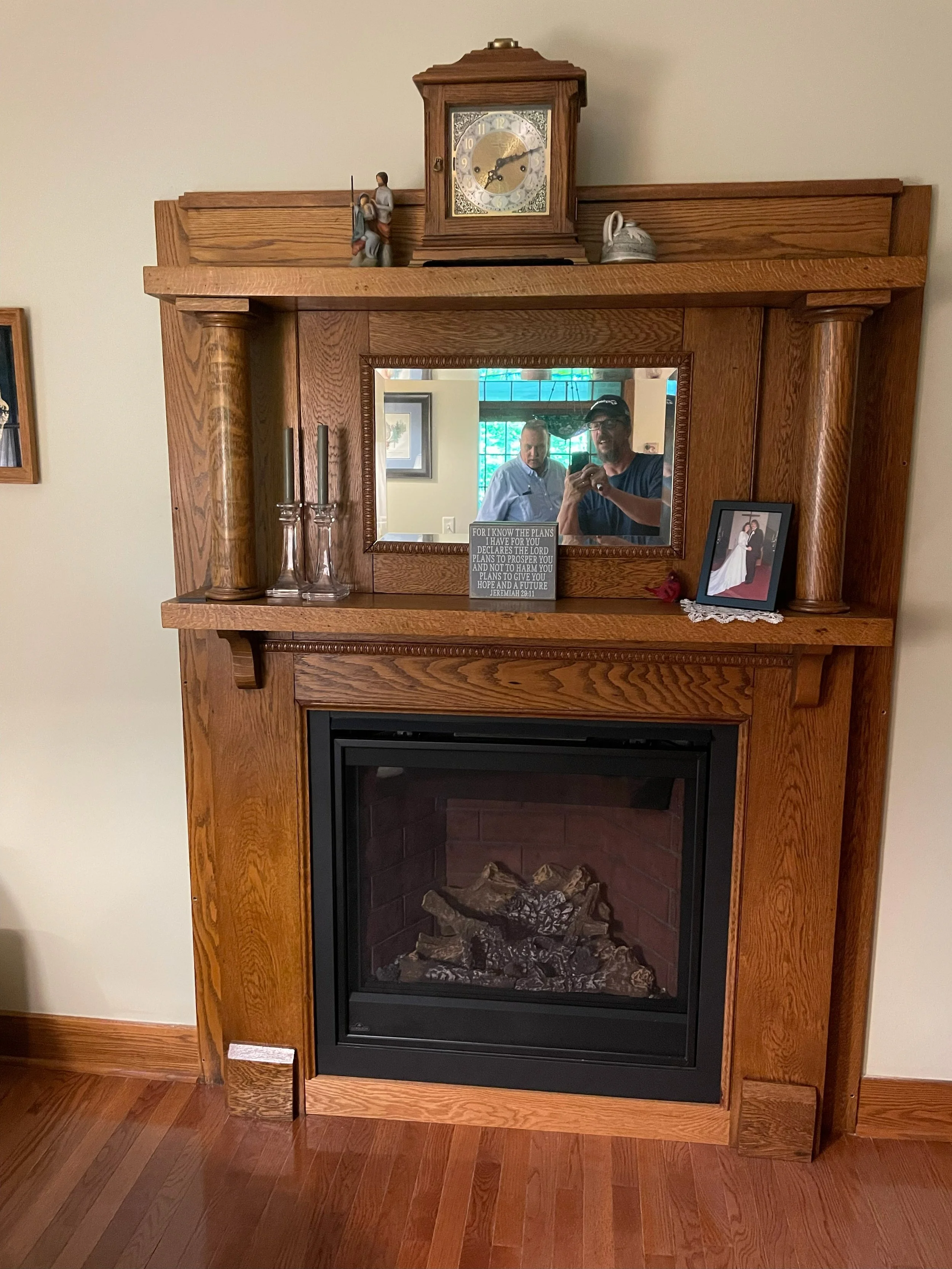 A wooden fireplace mantel with a mirror above it.