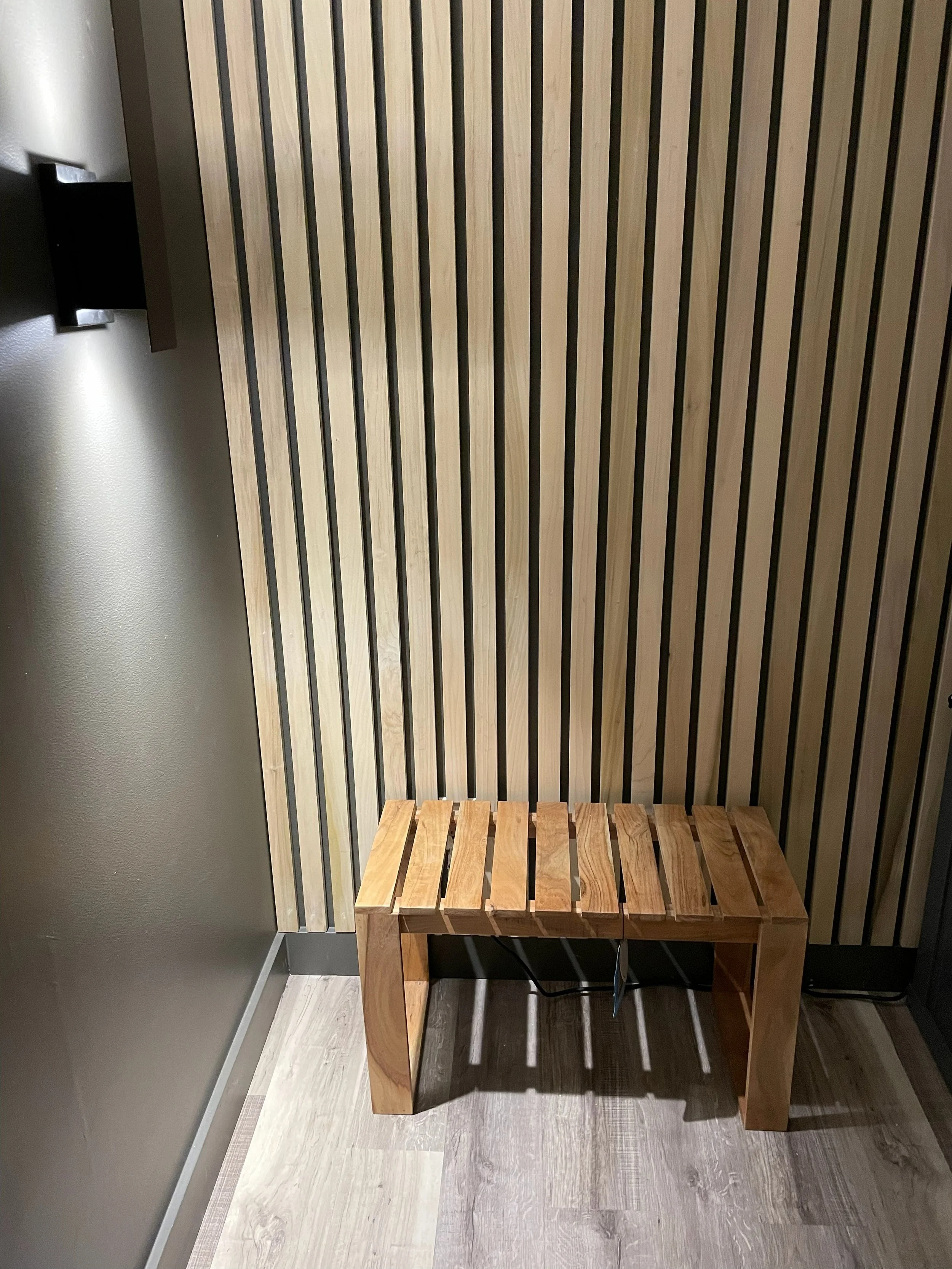 Wooden bench against a wall with vertical wooden slats in a modern interior setting.