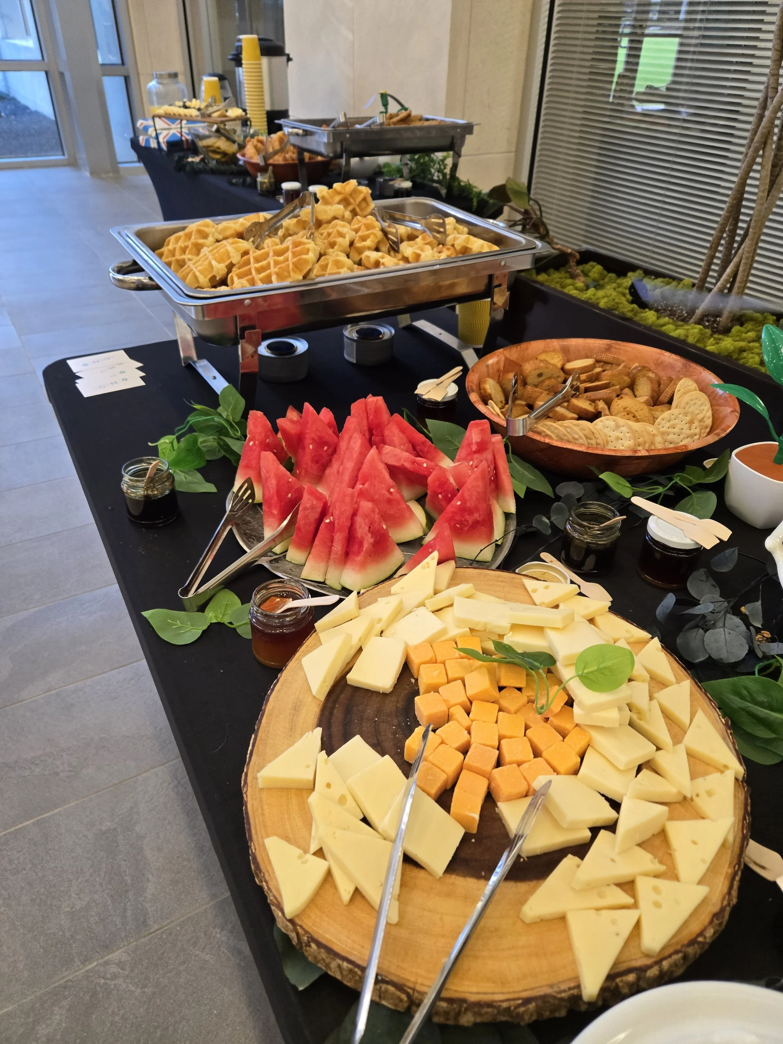 Artisan cheese board with sliced watermelon, crackers, and house jam on a wooden tray by Acento catering in Austin TX