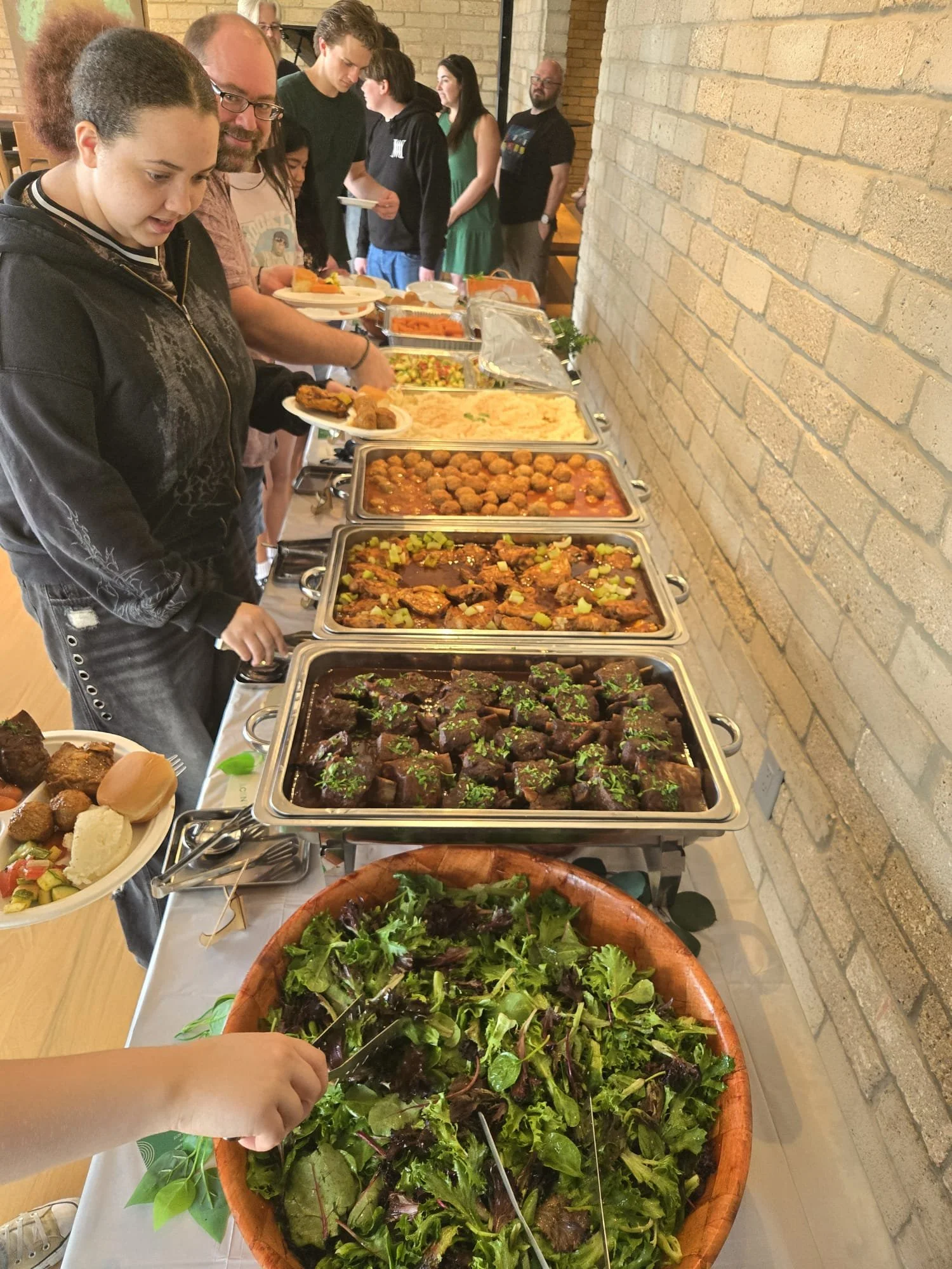 Guests enjoying a drop-off catering buffet featuring fresh salads, warm entrees, and side dishes by Acento in Austin TX