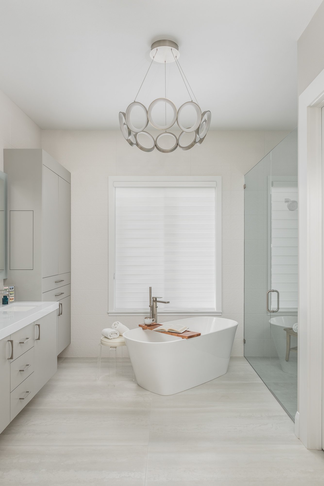custom primary bathroom that features A Statement Chandelier Above the Freestanding Tub | Lindross Remodeling