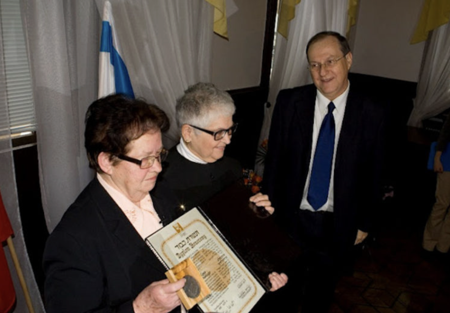  Zofia Grocholski (far left), the daughter of Maria and Stanislaw Grocholski, with Sally Frishberg (center) and then-Israeli Ambassador to Poland  Zvi Rav-Ner, receiving a certificate and medal acknowledging her and her family as Righteous Among the 