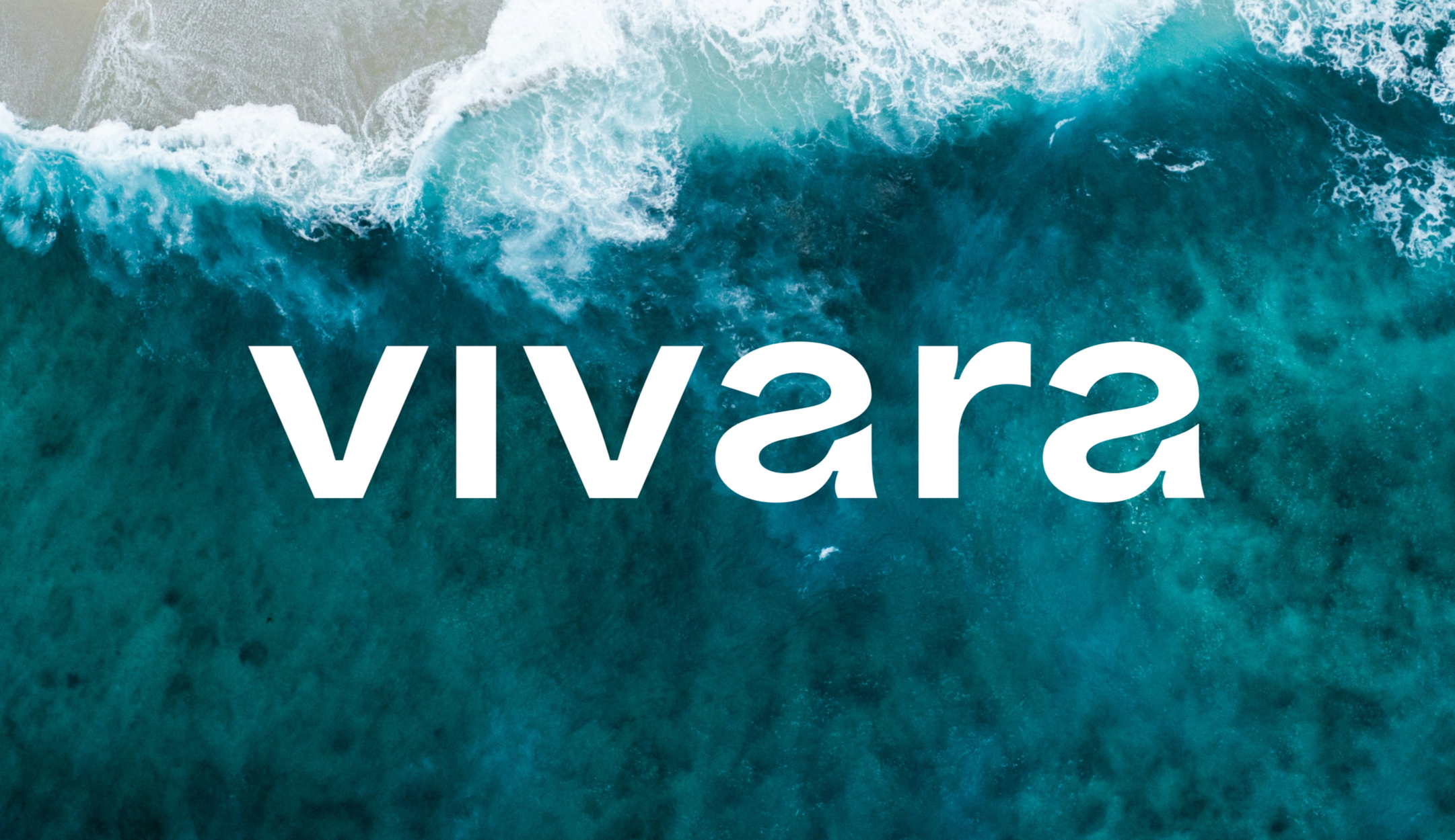 Aerial view of a large ocean wave crashing onto a sandy beach with the word 'viva' overlaid.