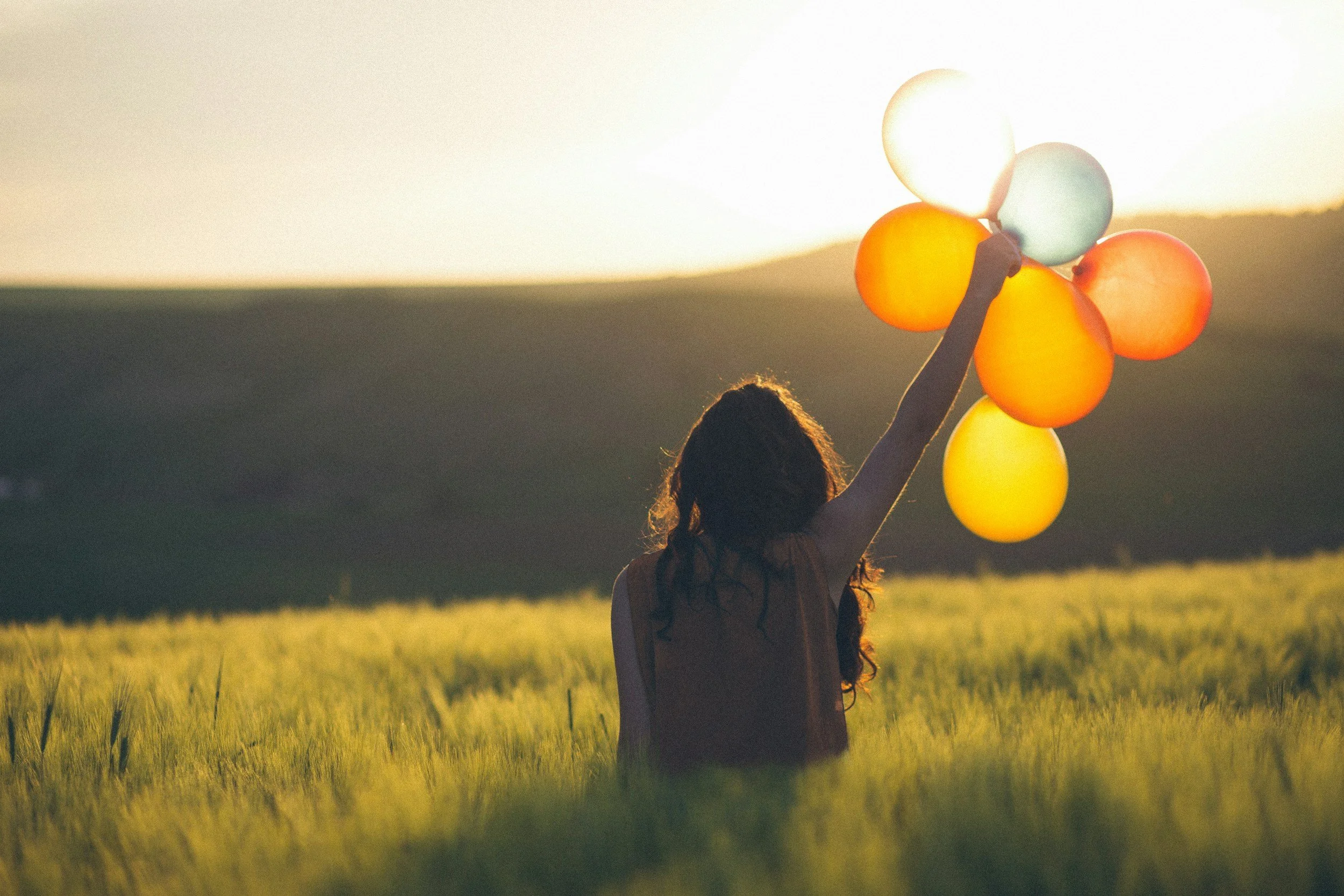 woman in a field holding balloons after she completed Brainspotting therapy online in california