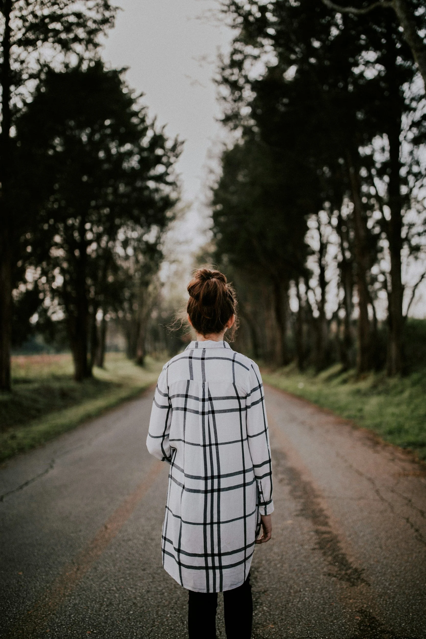 picture of woman from the back walking down a road lined by trees contemplating starting birth trauma therapy online in california